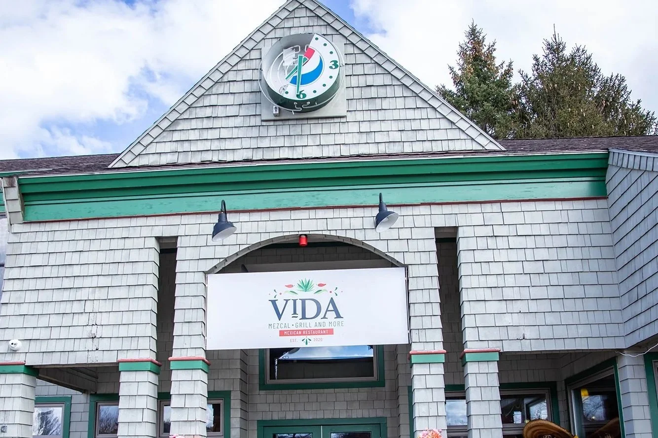 Exterior of Vida Mexican restaurant featuring mezcal and grill dining, with a shingle facade and rooftop clock sign.