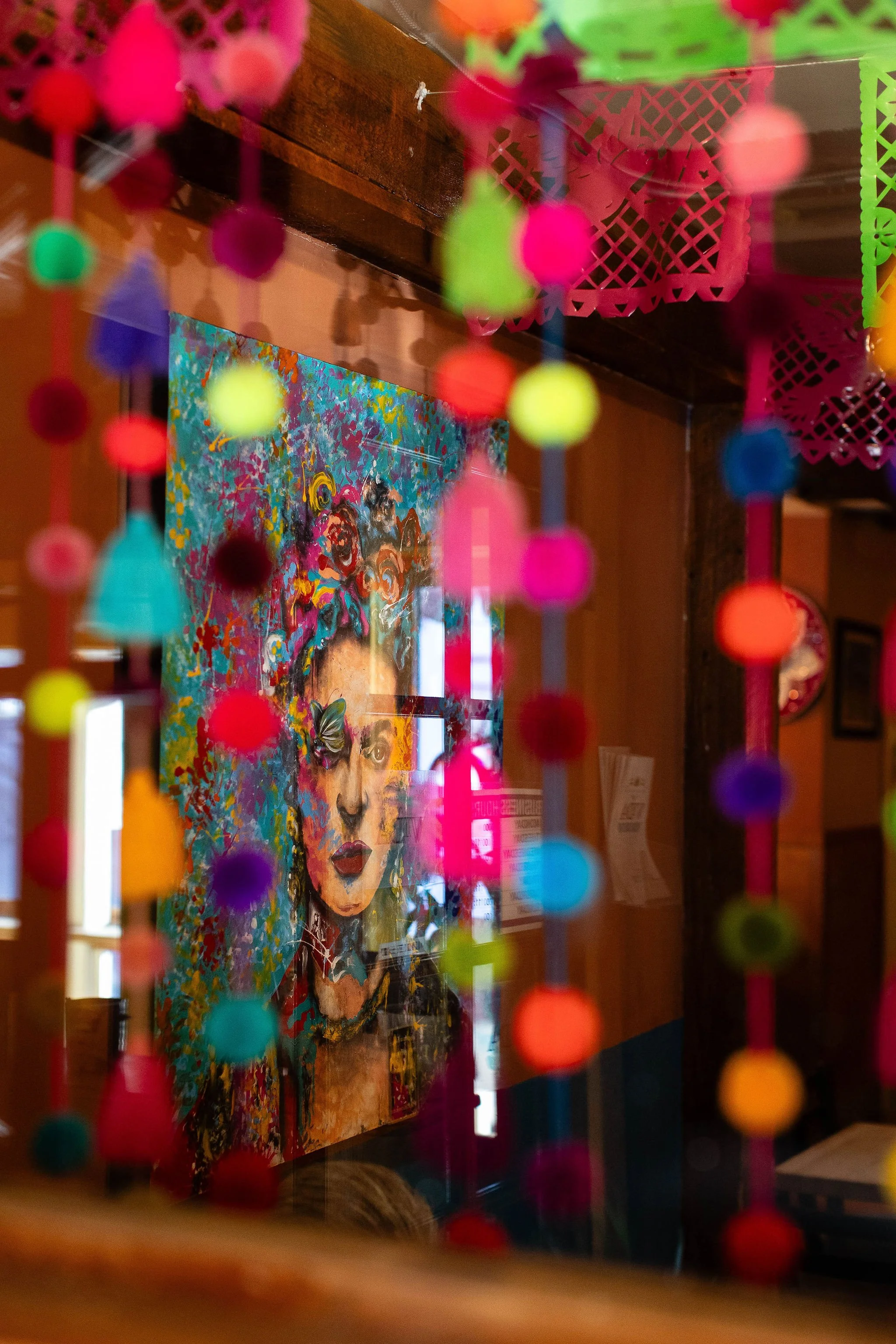 Colorful blurred paper garland surrounding a vibrant portrait painting in an art-filled interior