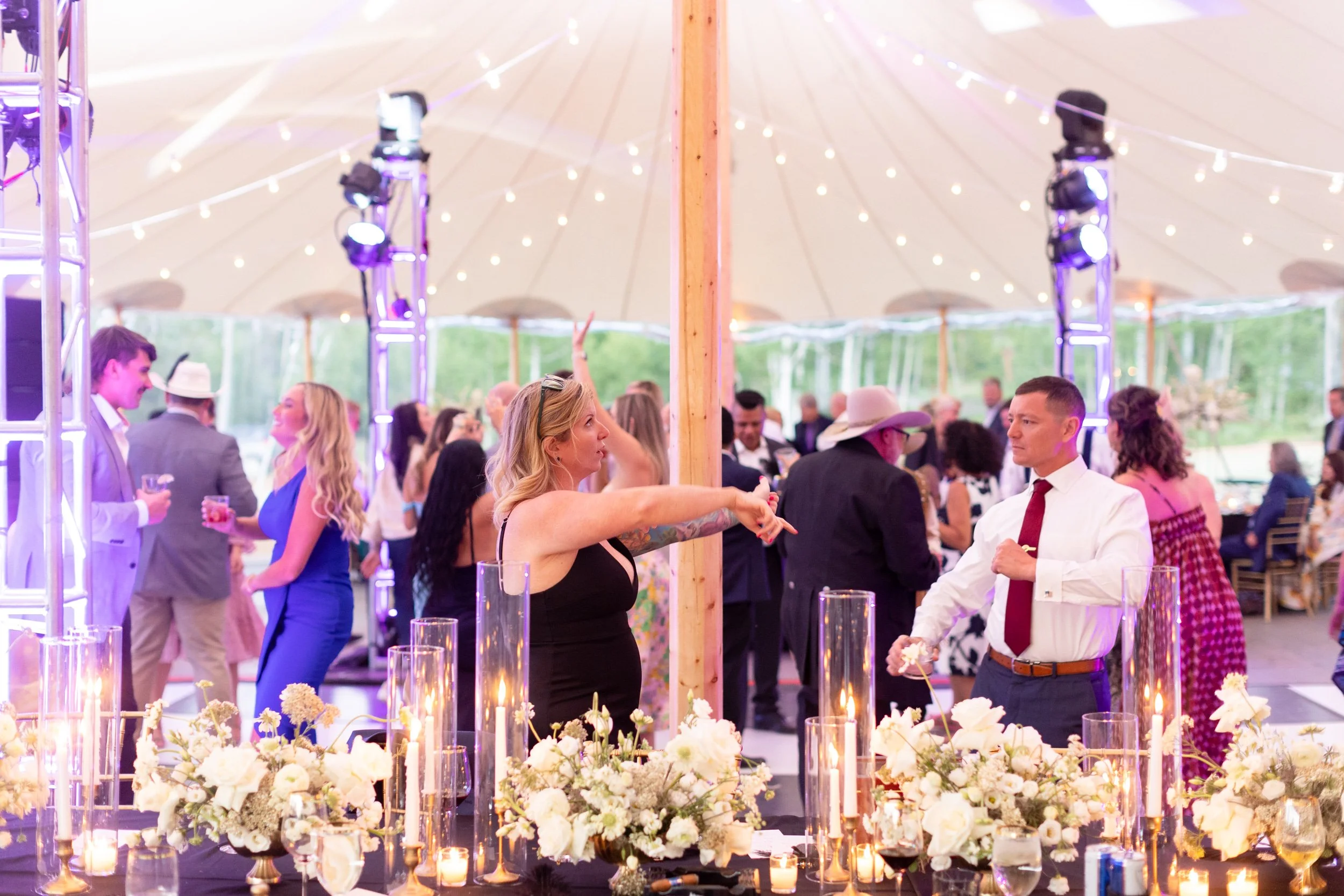 Reception tables under a white tent with string lights and florals at Tundra Springs, Colorado mountain wedding venue