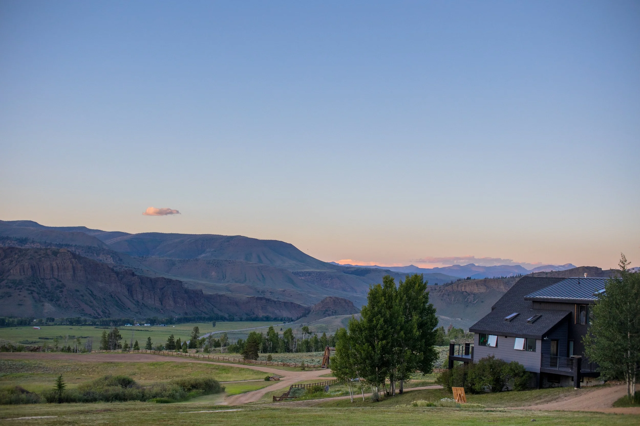 Dusk sky over a valley with a log home, meadows and cliffs in Hot Sulphur Springs, Colorado