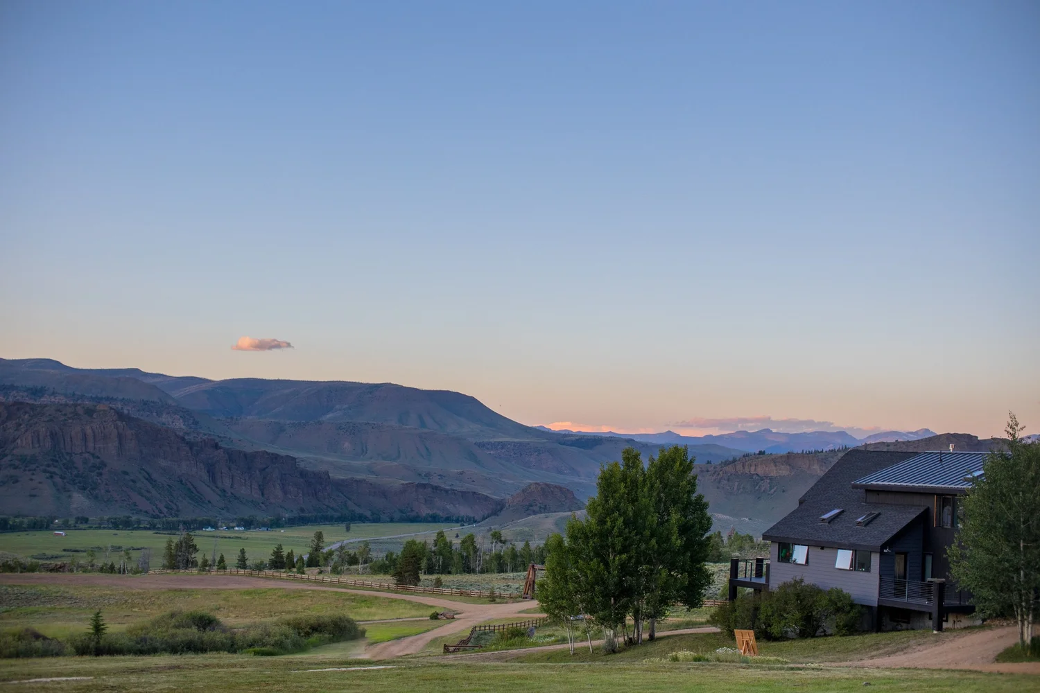 Dusk sky over a valley with a log home, meadows and cliffs in Hot Sulphur Springs, Colorado