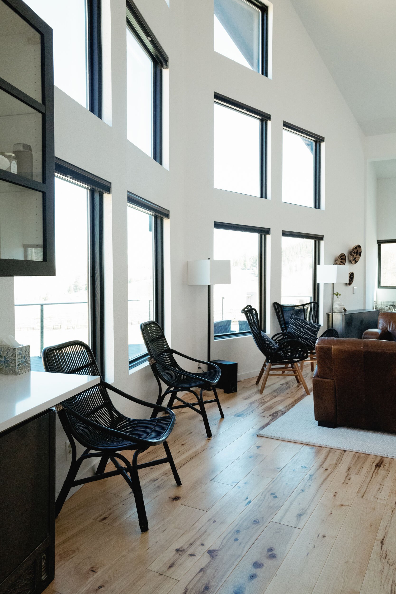 Lounge with black leather chairs beside tall windows and wood floors at Tundra Springs, Colorado mountain wedding venue