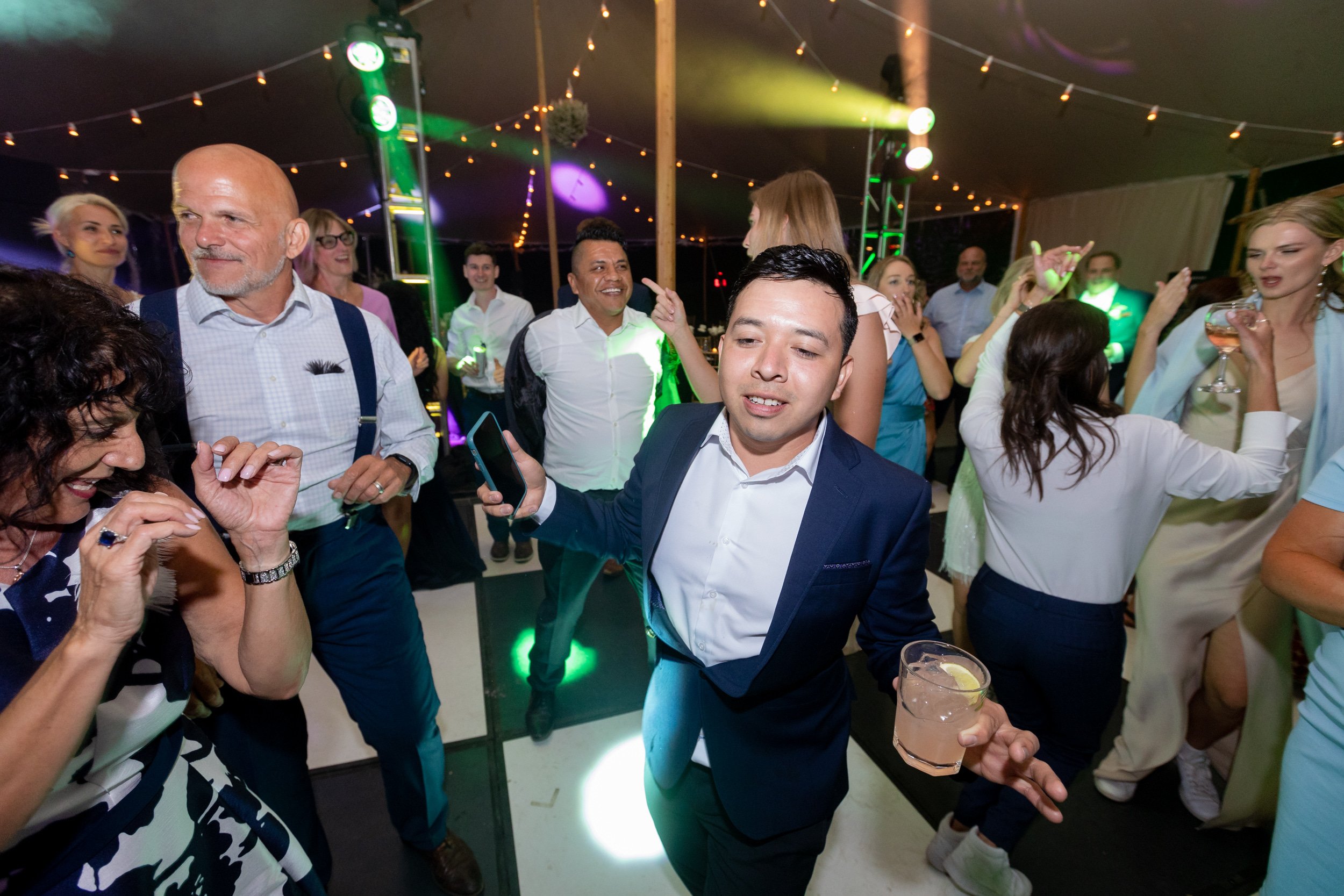 Wedding guests dancing under string lights in a tent at Tundra Springs, Colorado mountain wedding venue