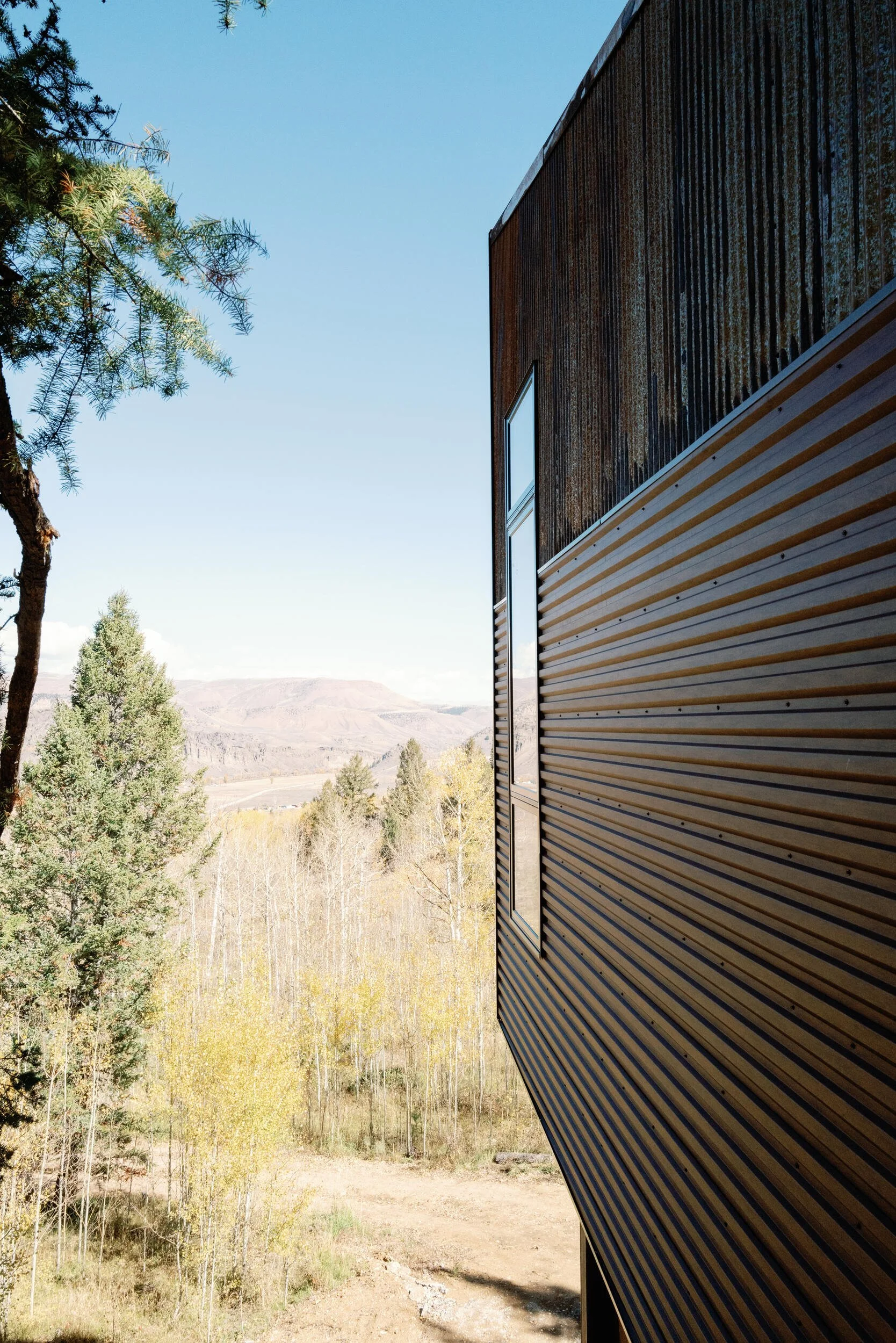 Dark wood-clad tree house exterior with a view over aspens and hills at Tundra Springs, Colorado mountain wedding venue