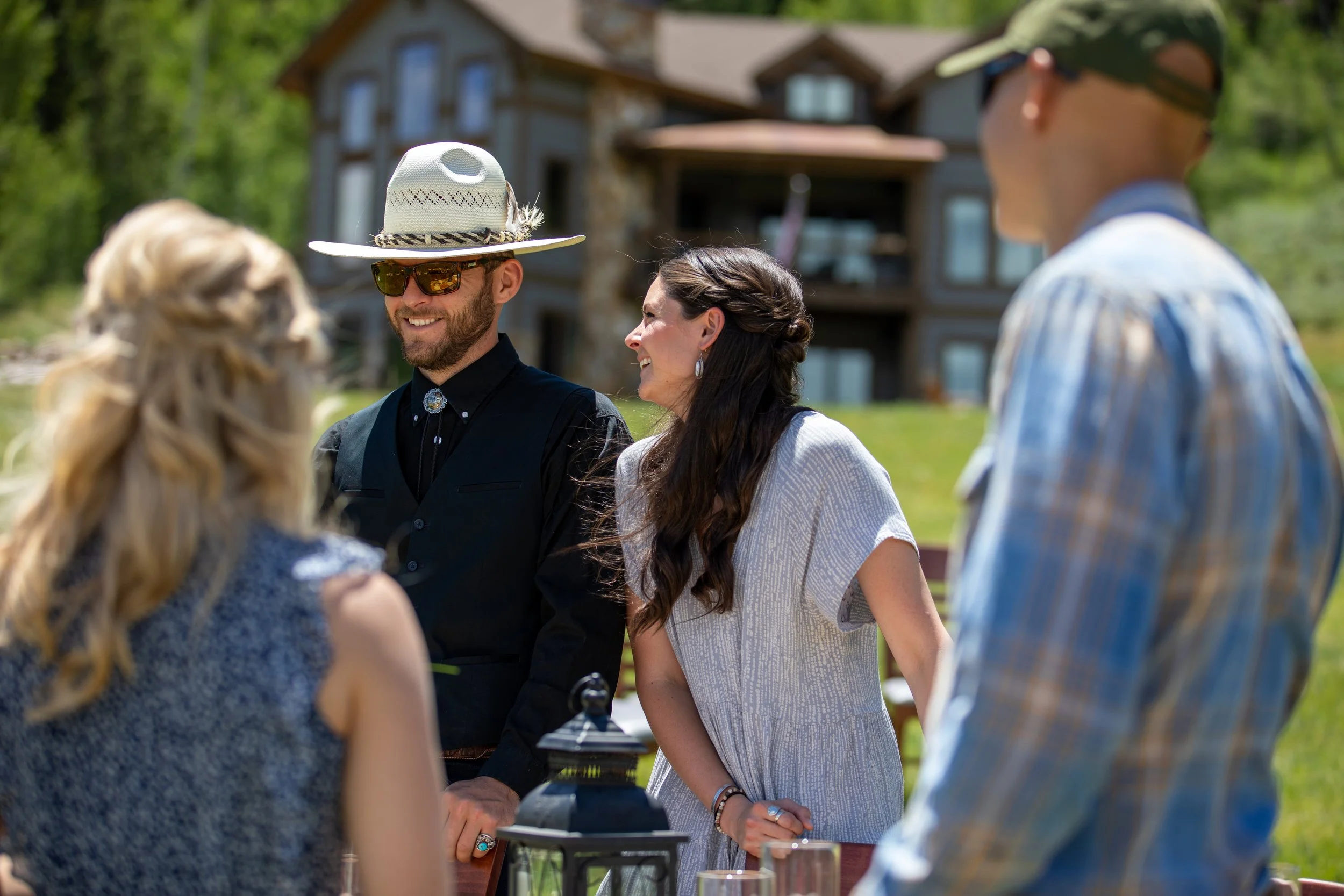 Wedding guests chatting outdoors beside a timber lodge at Tundra Springs, Colorado mountain wedding venue