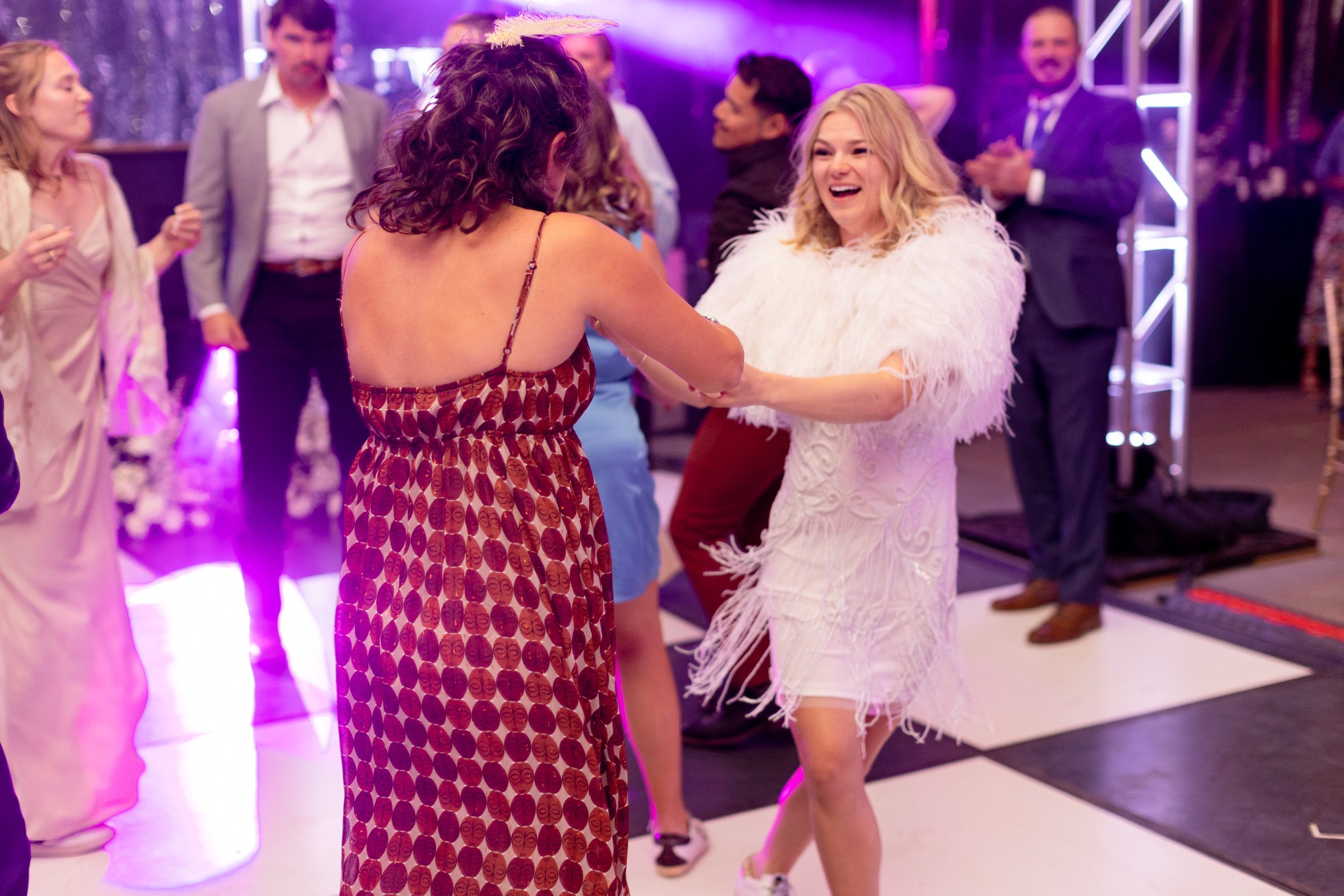 Guests dancing on a checkered floor under purple stage lights at a reception in Hot Sulphur Springs, Colorado