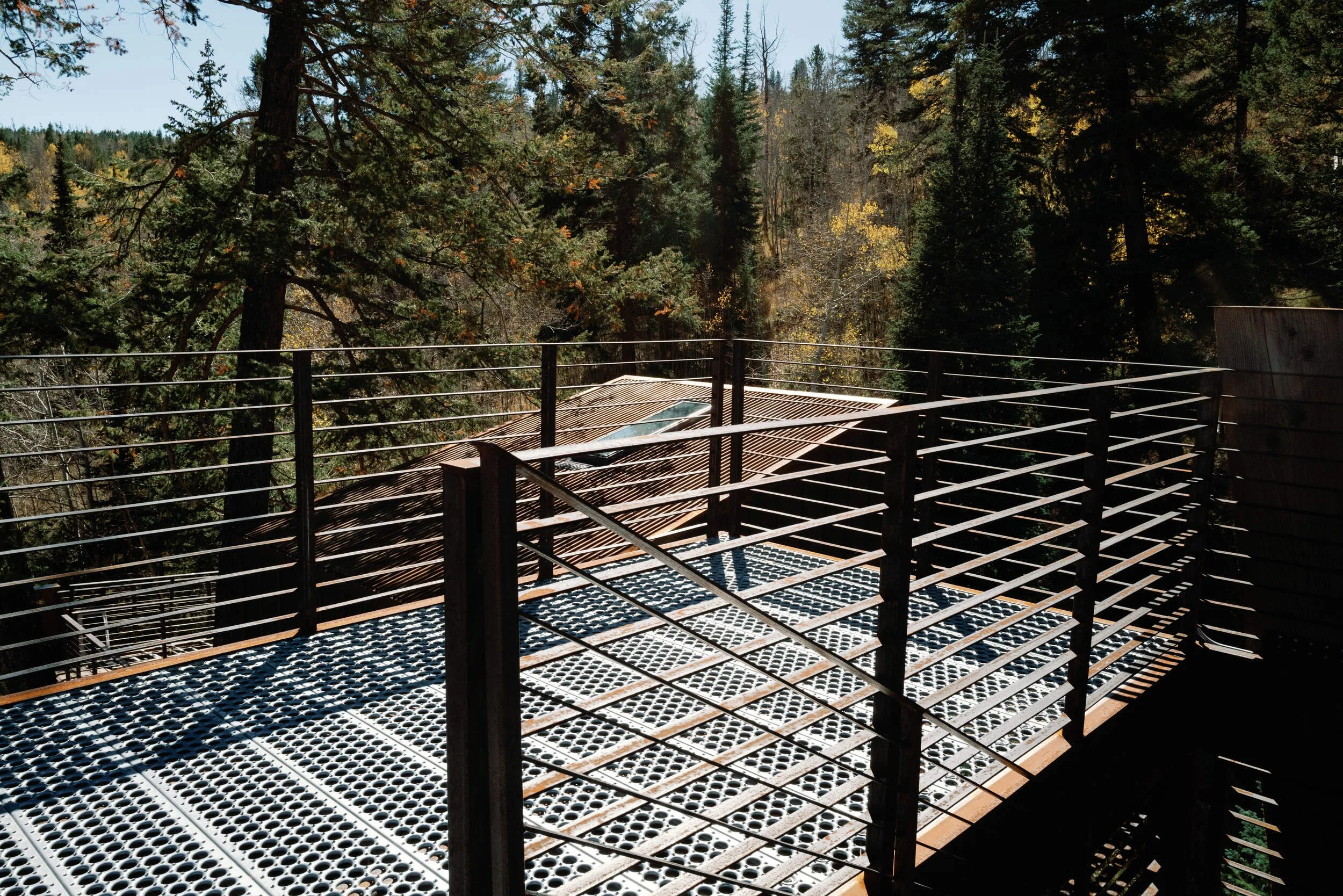 Metal-mesh deck with cable railings beside dark wood walls at Tundra Springs, Colorado mountain wedding venue
