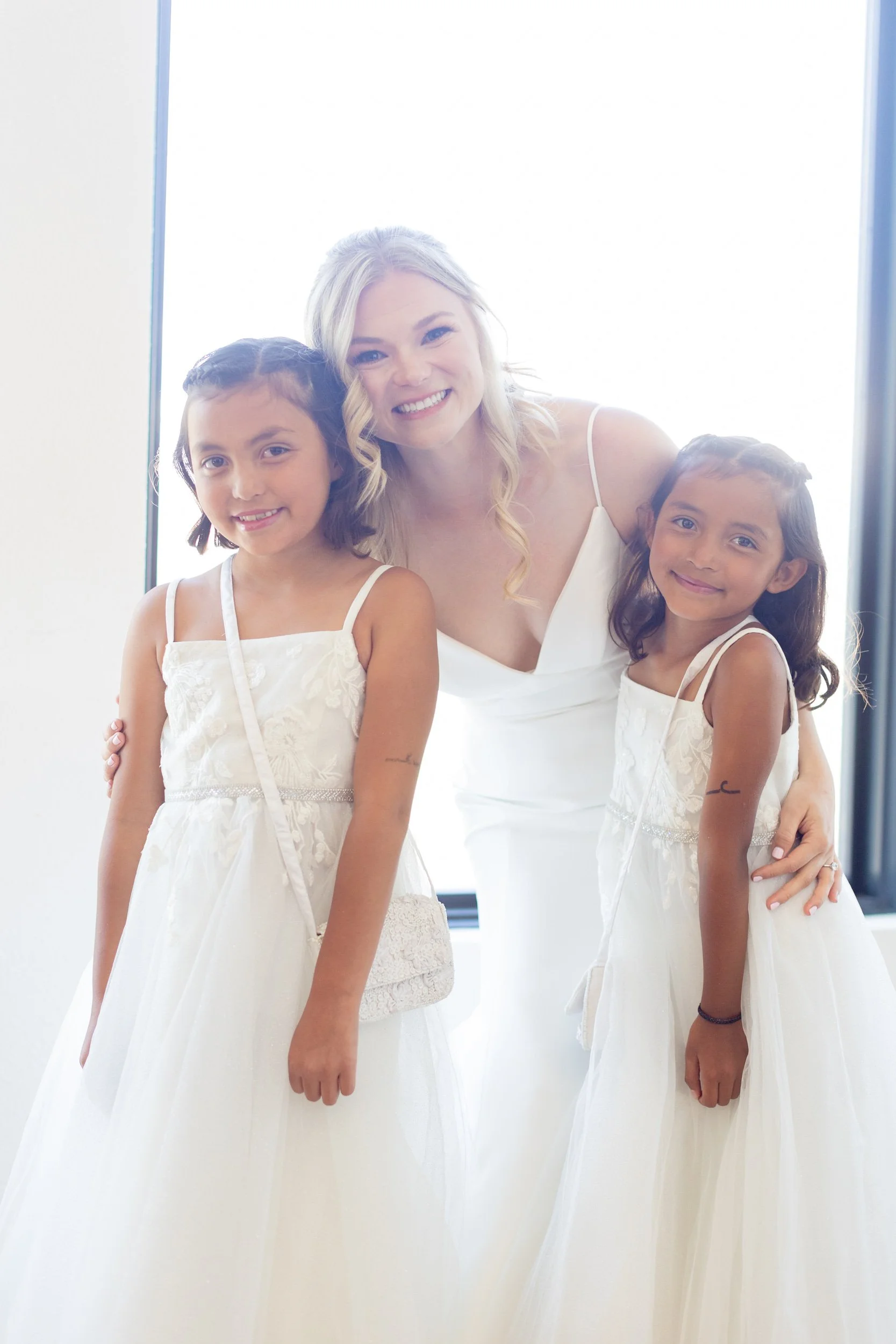 Smiling woman with two young flower girls in white dresses at Tundra Springs, Colorado mountain wedding venue