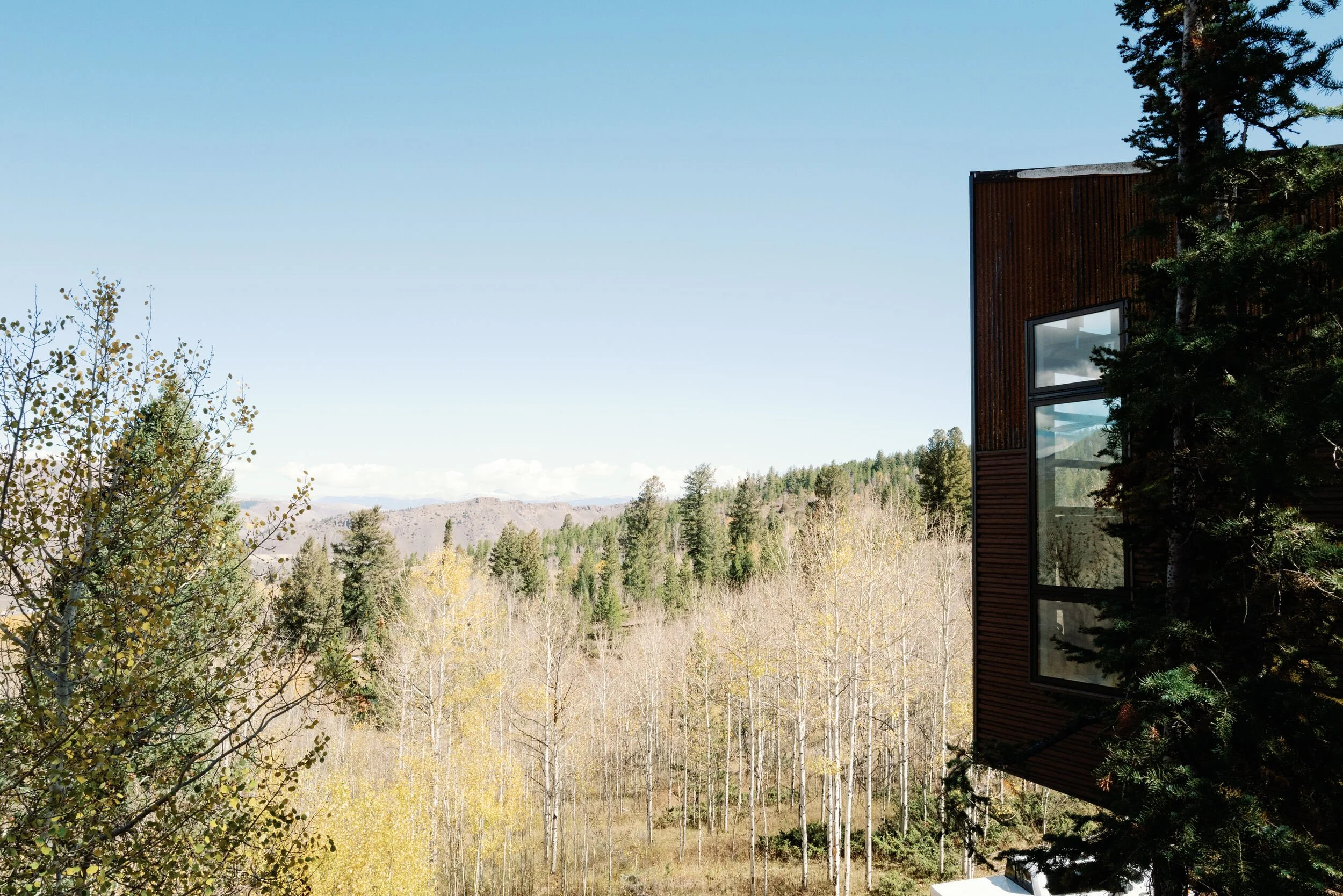 Modern wood-sided lodge overlooking forest and distant peaks in Hot Sulphur Springs, Colorado