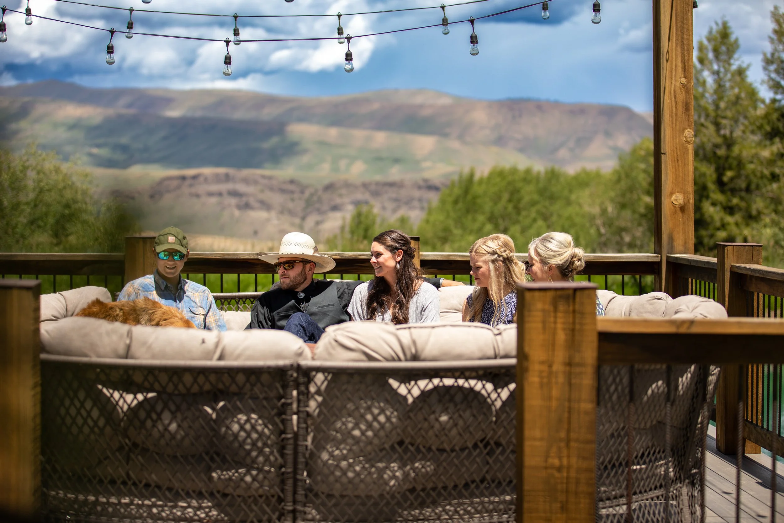 Guests on a covered deck with a cushioned sofa, string lights and mountain views in Hot Sulphur Springs, Colorado