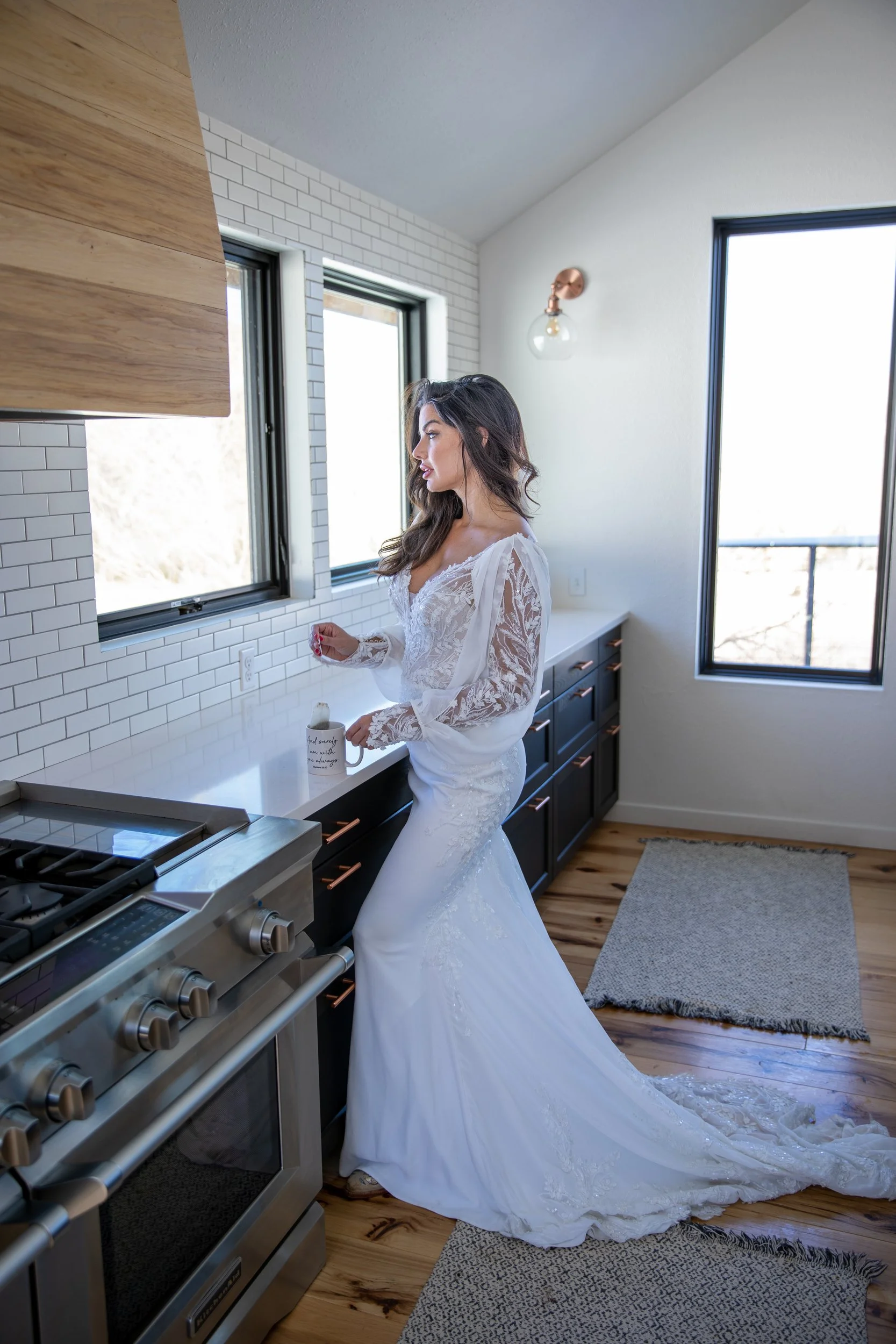 Bride in a white gown in a modern cabin kitchen beside a window in Hot Sulphur Springs, Colorado
