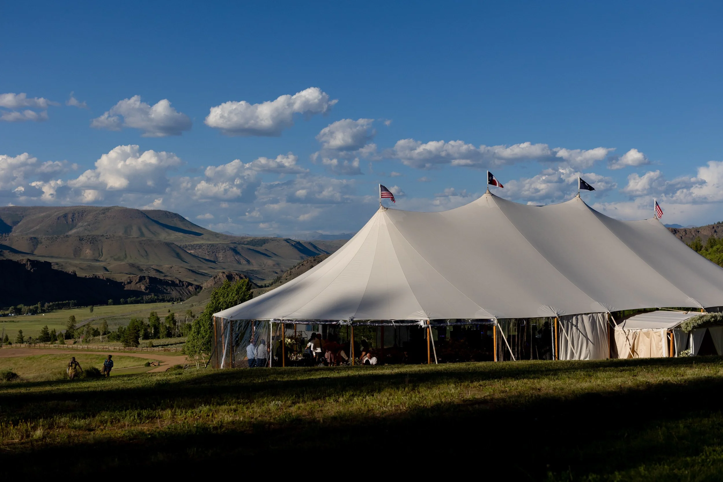 Illuminated white stretch tent glowing under a deep blue dusk sky at Tundra Springs, Colorado mountain wedding venue