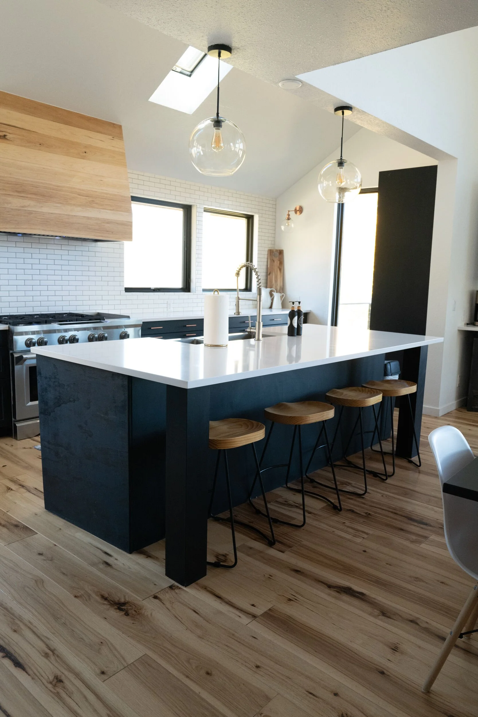 Modern kitchen with a dark island, bar stools and wood-slat accents at Tundra Springs, Colorado mountain wedding venue