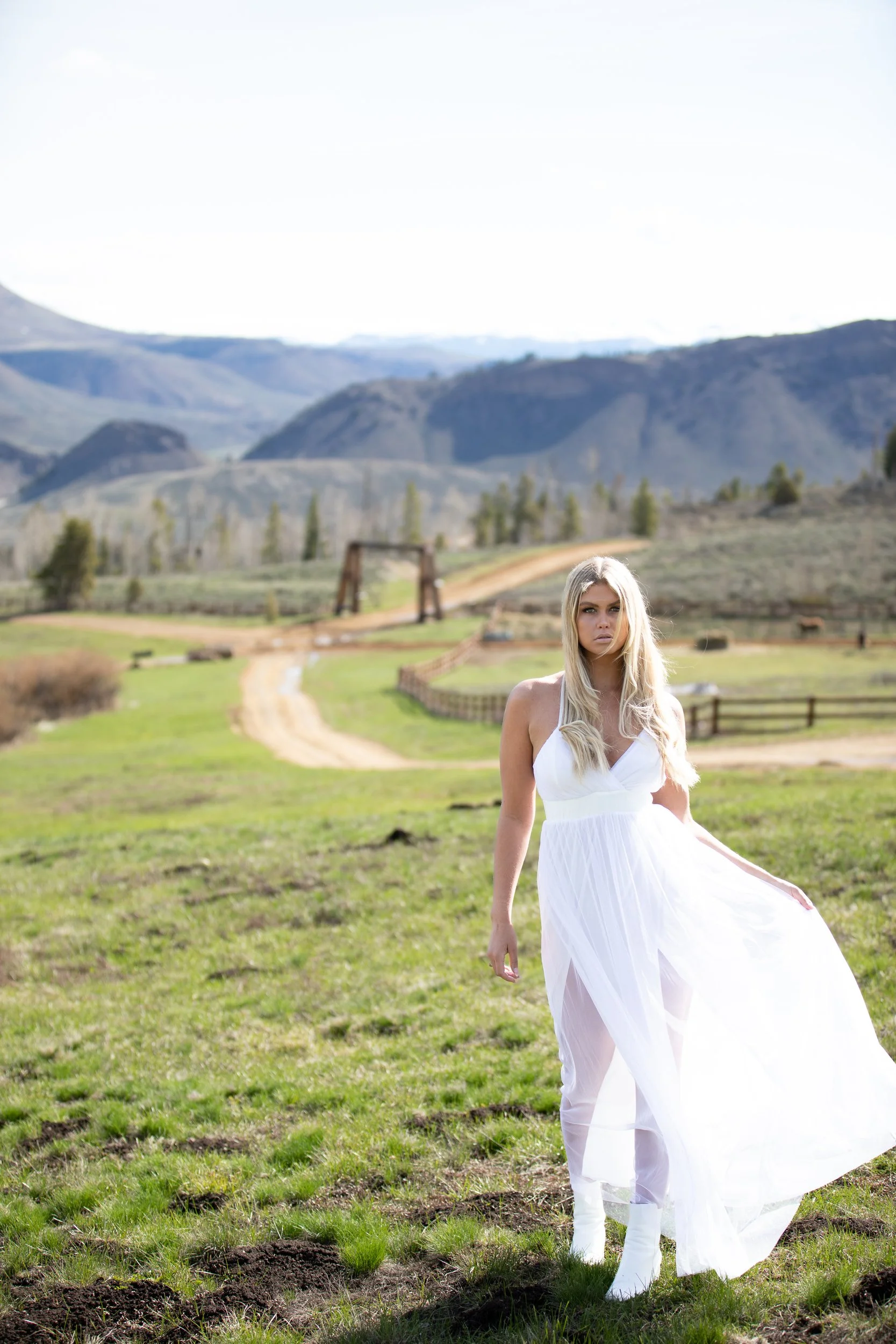 Bride in a white gown walking a grassy path toward mountain ridges in Hot Sulphur Springs, Colorado
