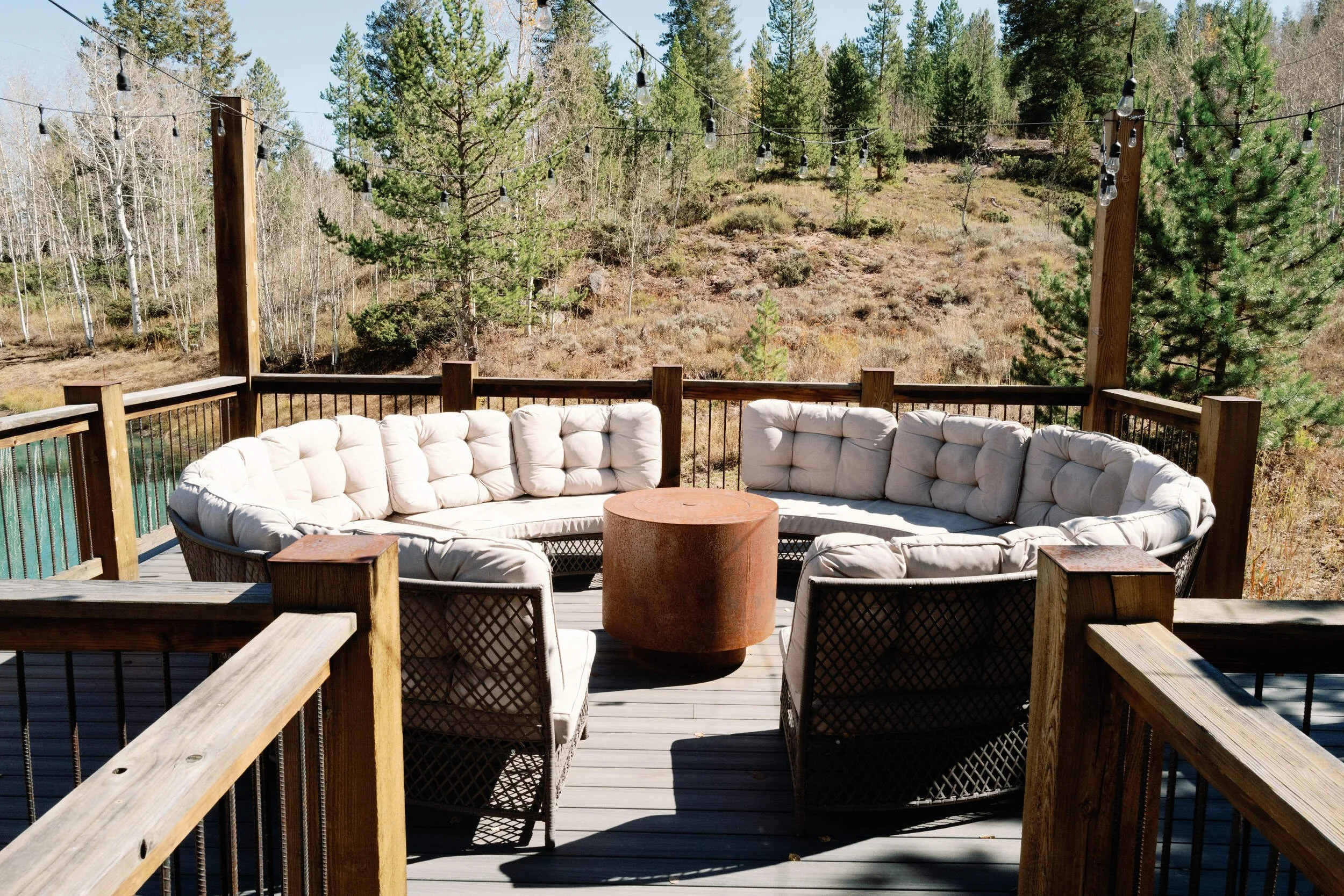 Round deck with a cream cushioned sectional beside wood railings at Tundra Springs, Colorado mountain wedding venue