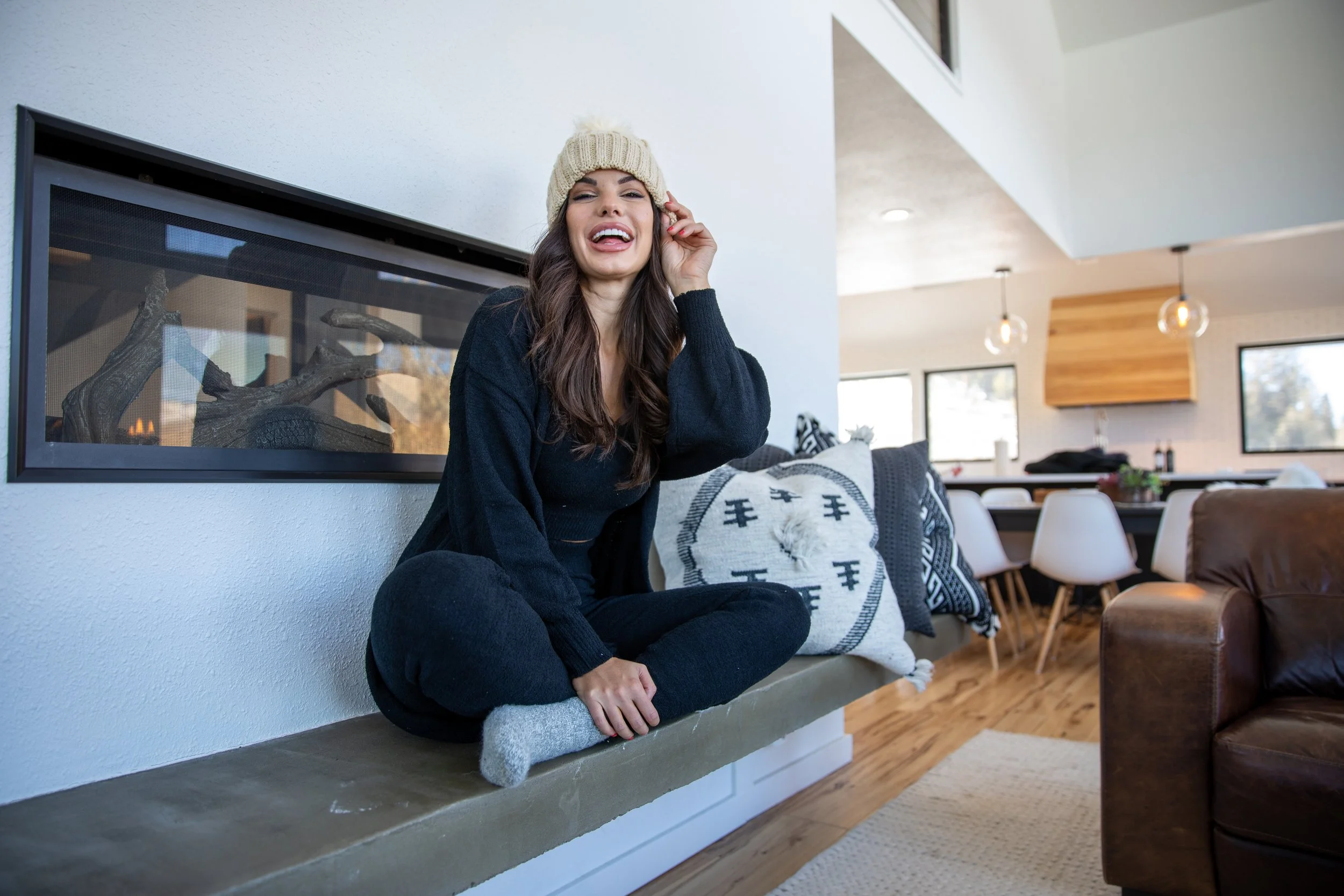 Woman in a beanie and black sweater on a bench in a modern cabin living room in Hot Sulphur Springs, Colorado