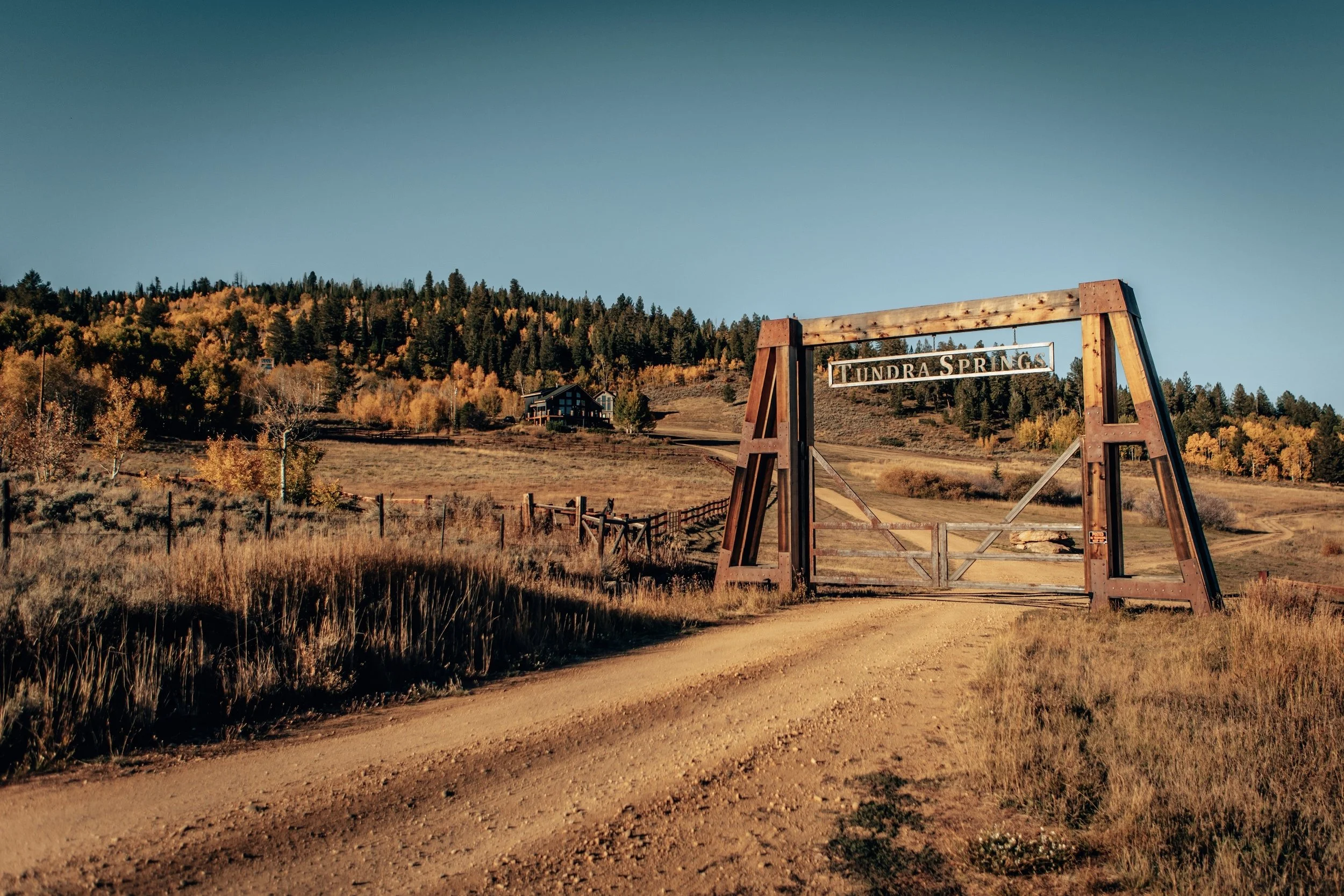 Rustic wooden bridge over a dirt road through golden fields in Hot Sulphur Springs, Colorado