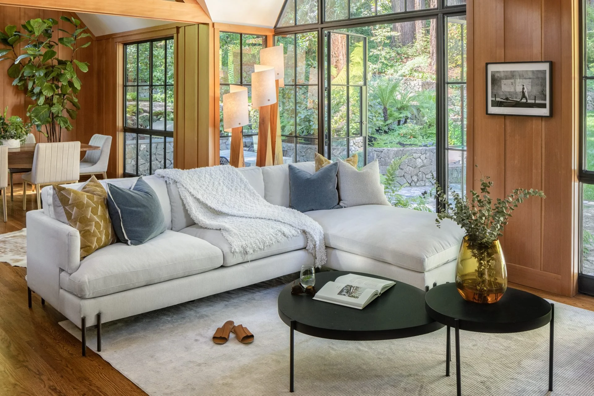 Living room with a white sectional below steel windows onto the redwoods, 16 Woodside, Mill Valley