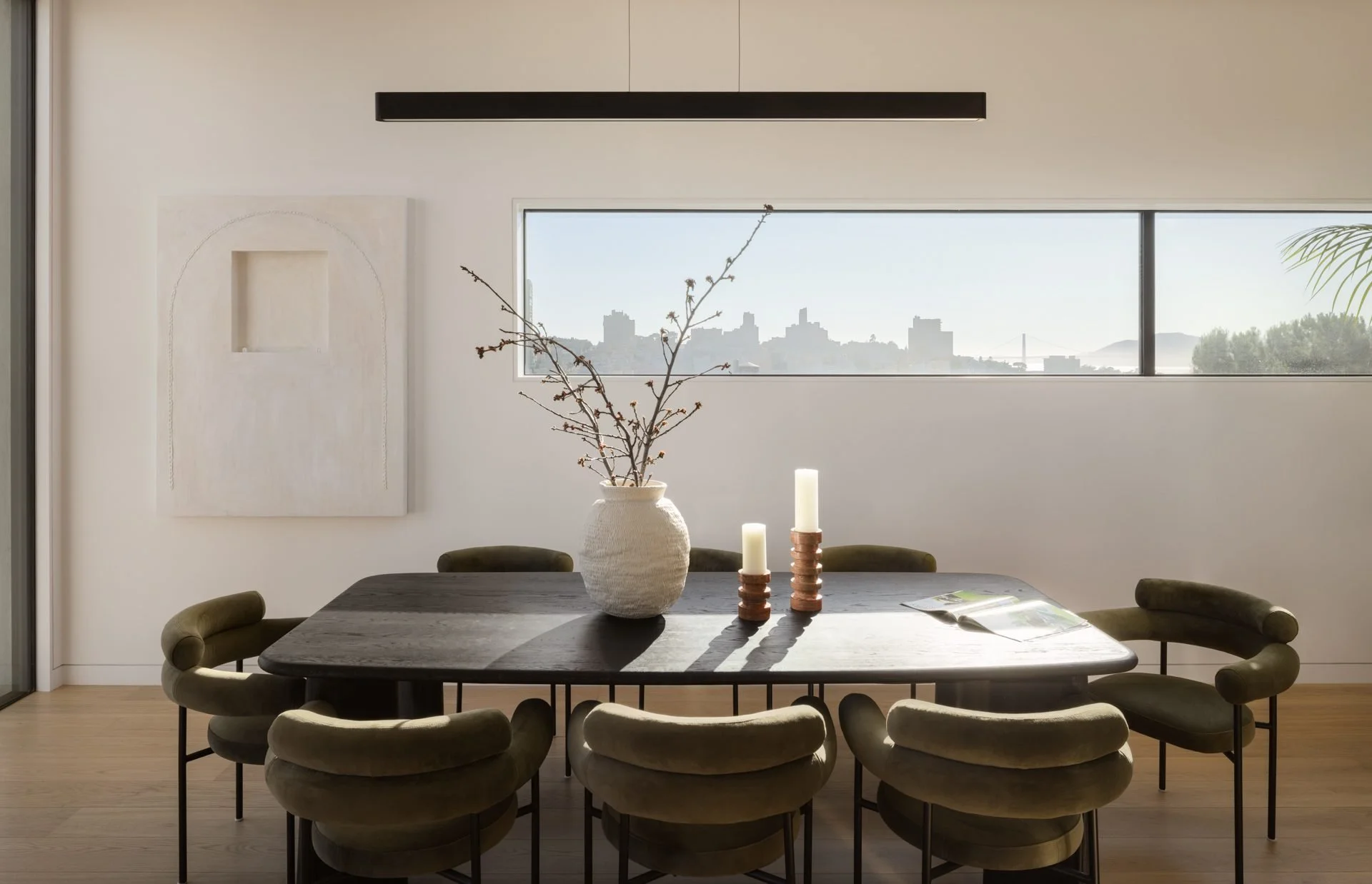 Dining room with a dark oak table, olive chairs and a ribbon window to the city, 119 Telegraph, San Francisco