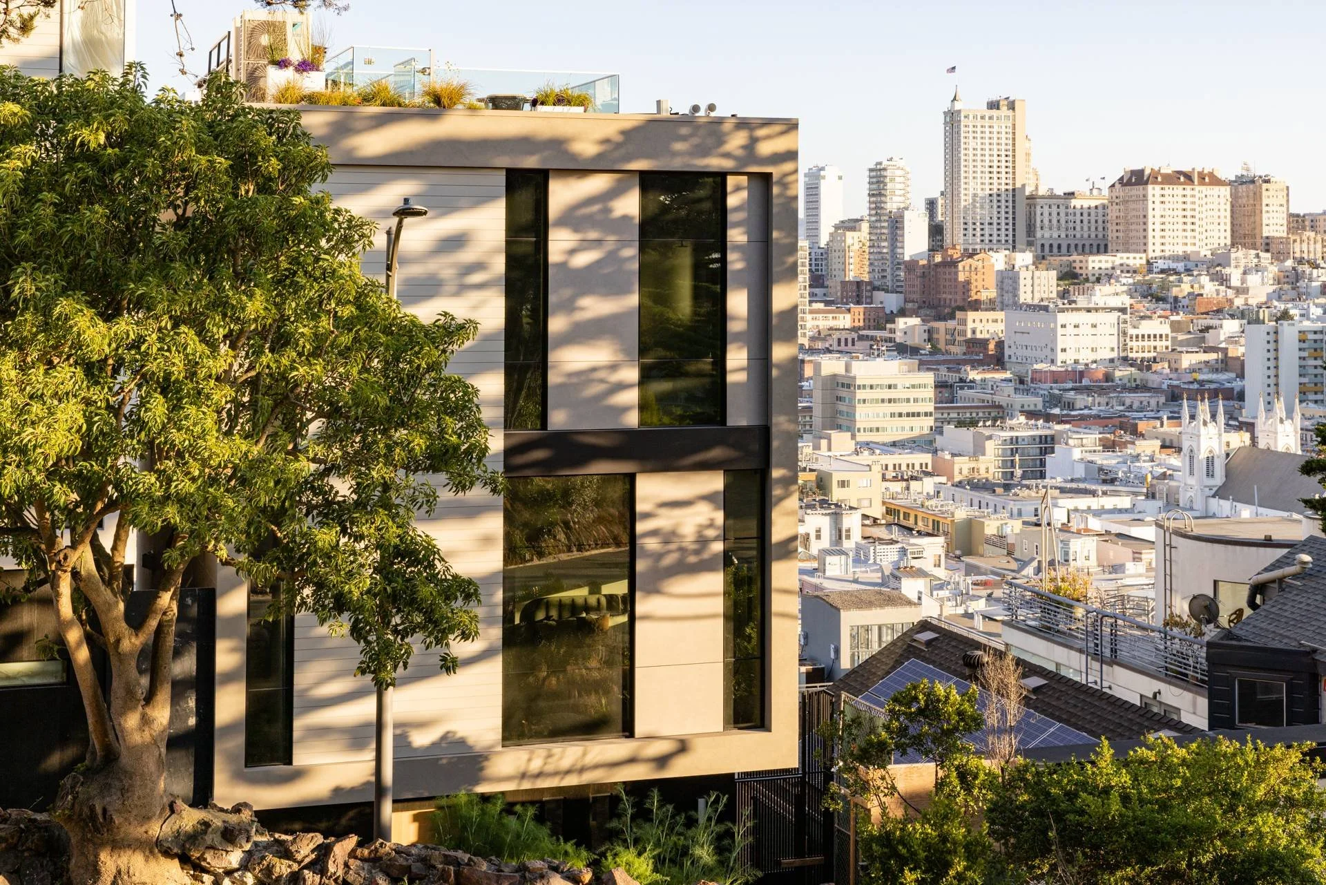 Aerial of the modern Telegraph Hill residence among trees with North Beach and the city beyond, 119 Telegraph, San Francisco