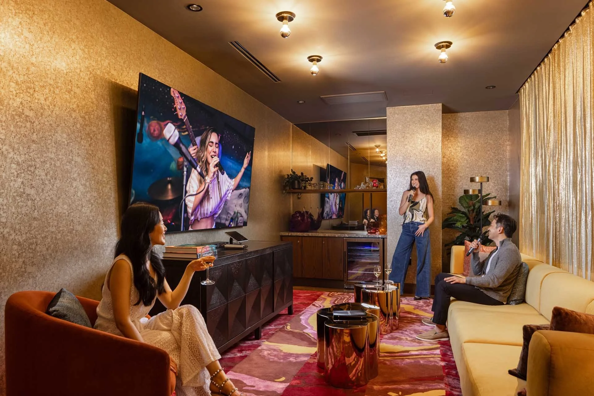 Residents relaxing in the gold-walled media lounge with a large screen and velvet seating, The Clara, Santa Clara