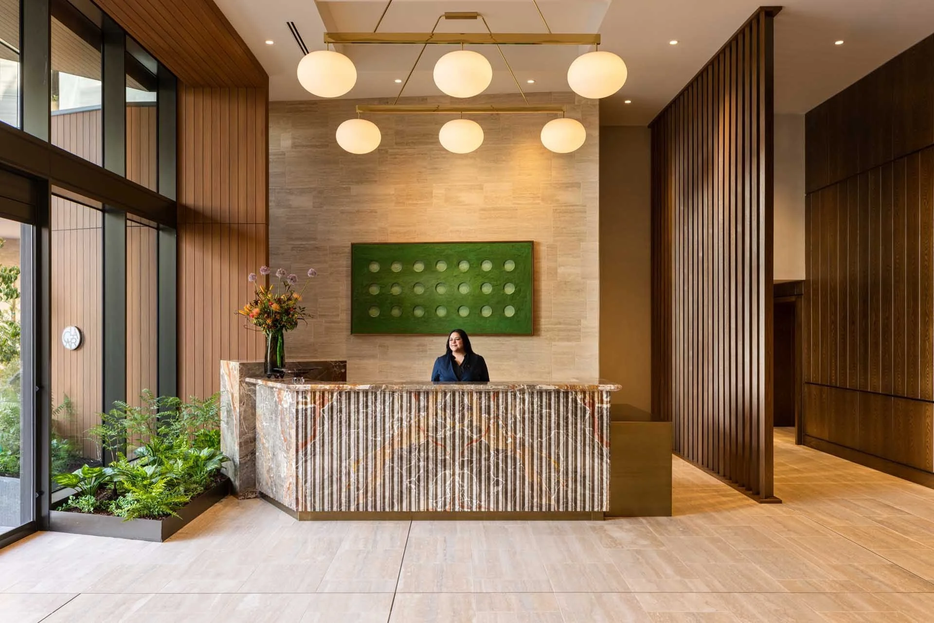 Lobby reception with a fluted stone desk, globe pendants and a green moss wall, The Clara, Santa Clara