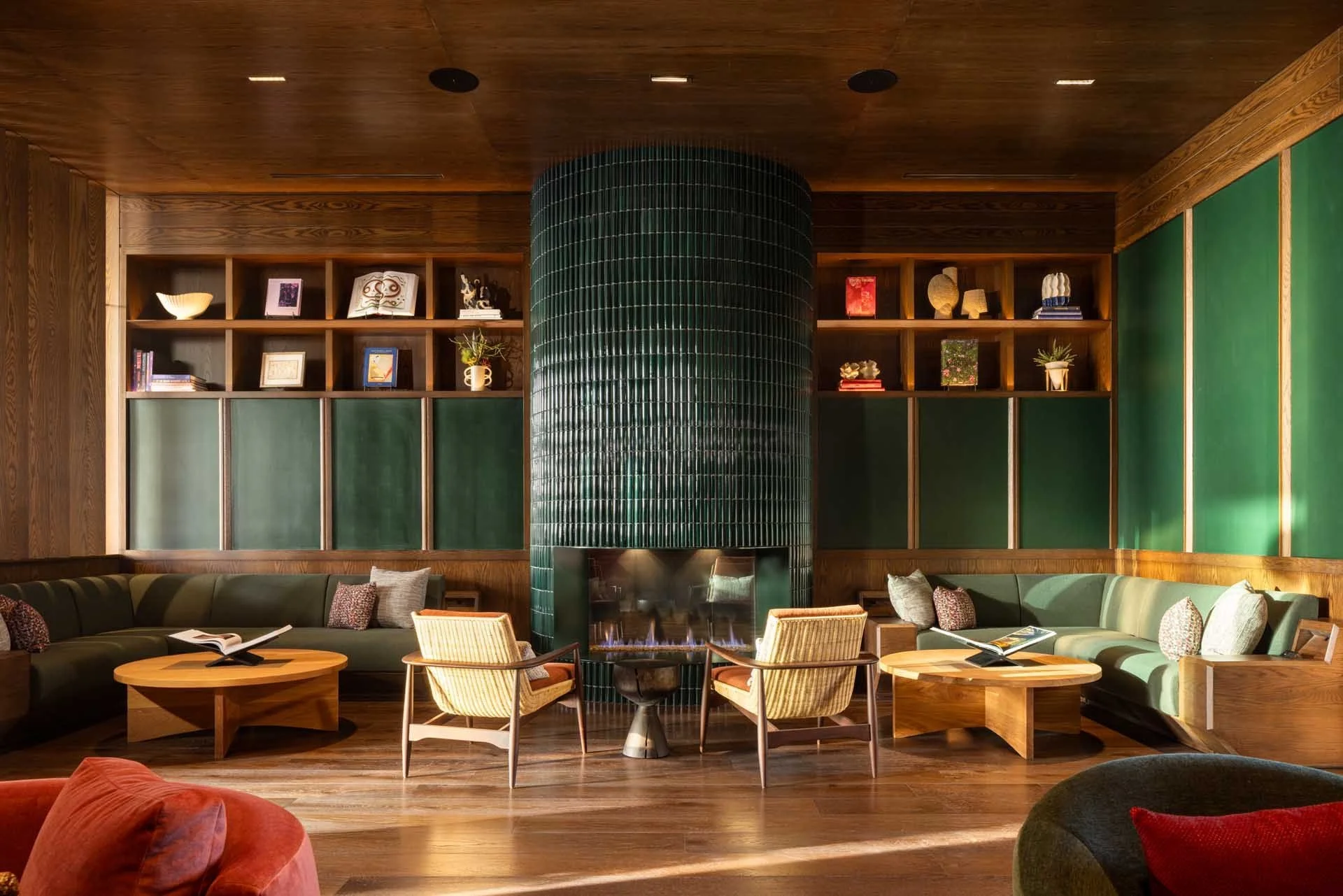 Redwood Den library lounge with walnut shelving, a green tiled column and lounge chairs, The Clara, Santa Clara