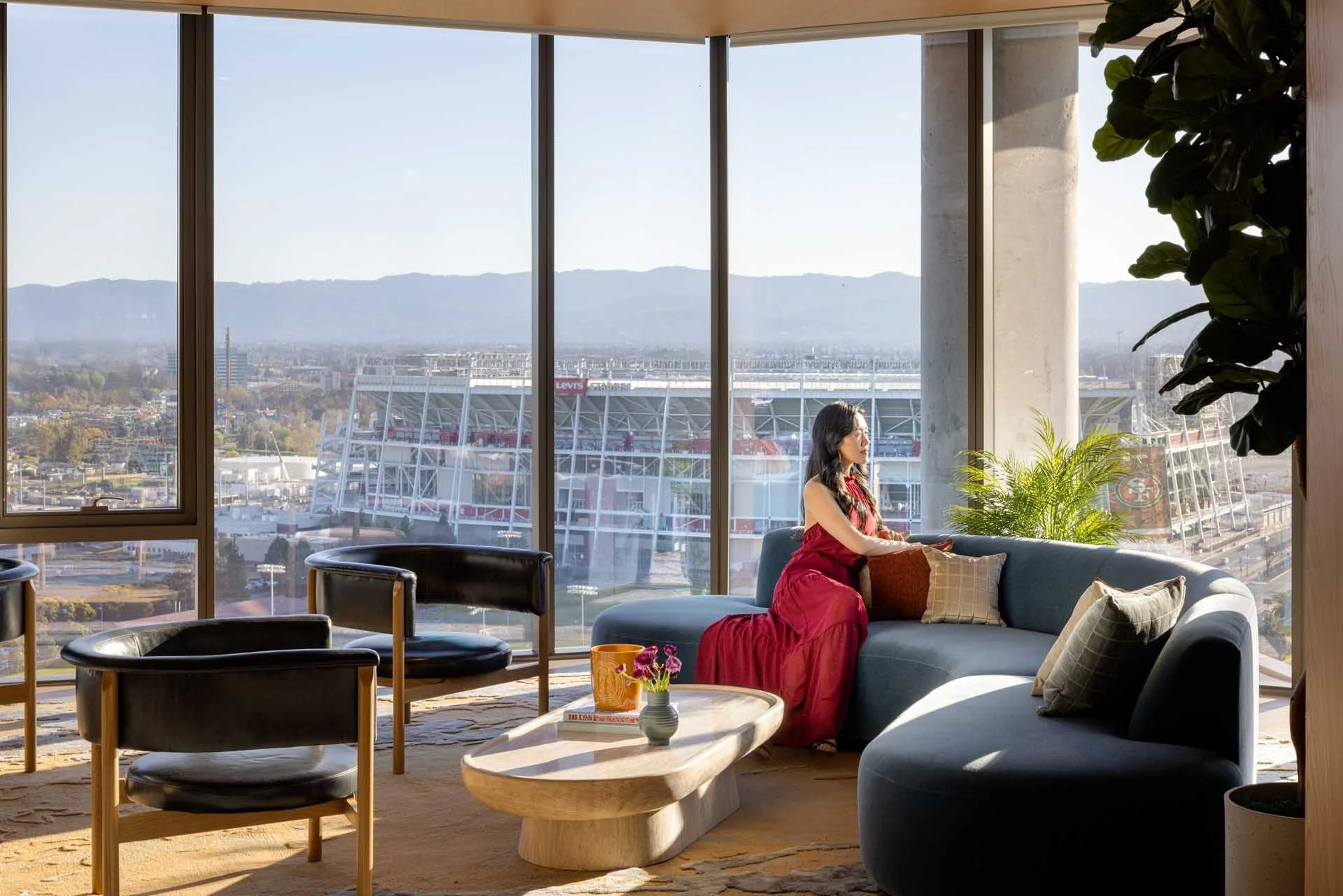 Corner residence with a curved blue sofa and floor-to-ceiling windows overlooking Levi's Stadium, The Clara, Santa Clara