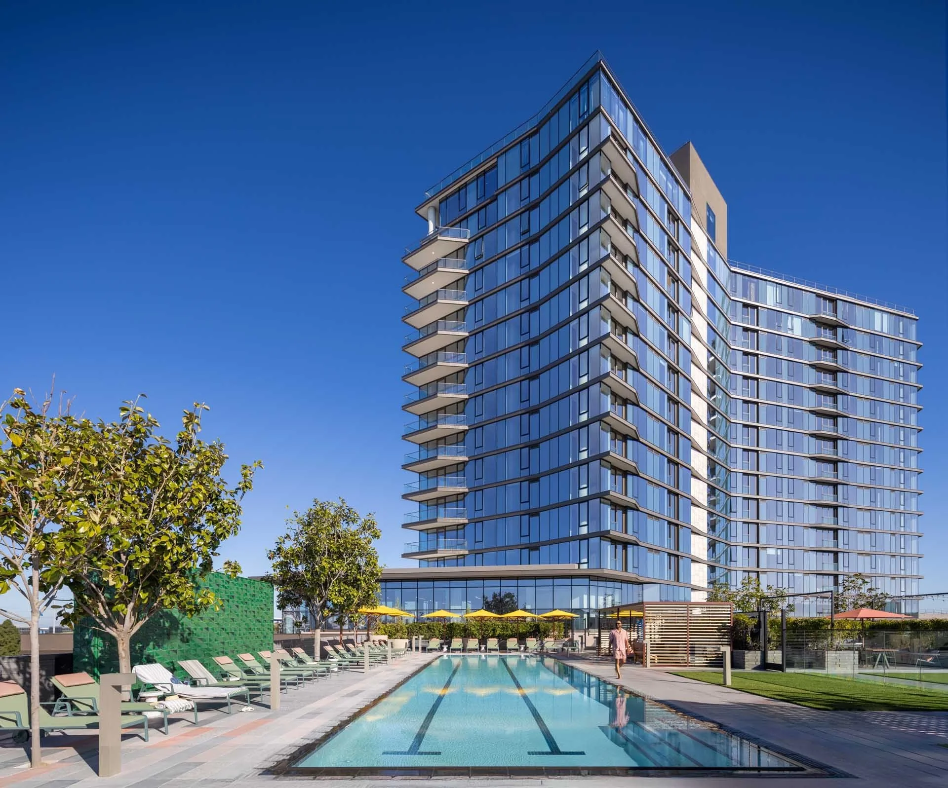 The Clara tower rising above the podium pool deck under a clear blue sky, Santa Clara