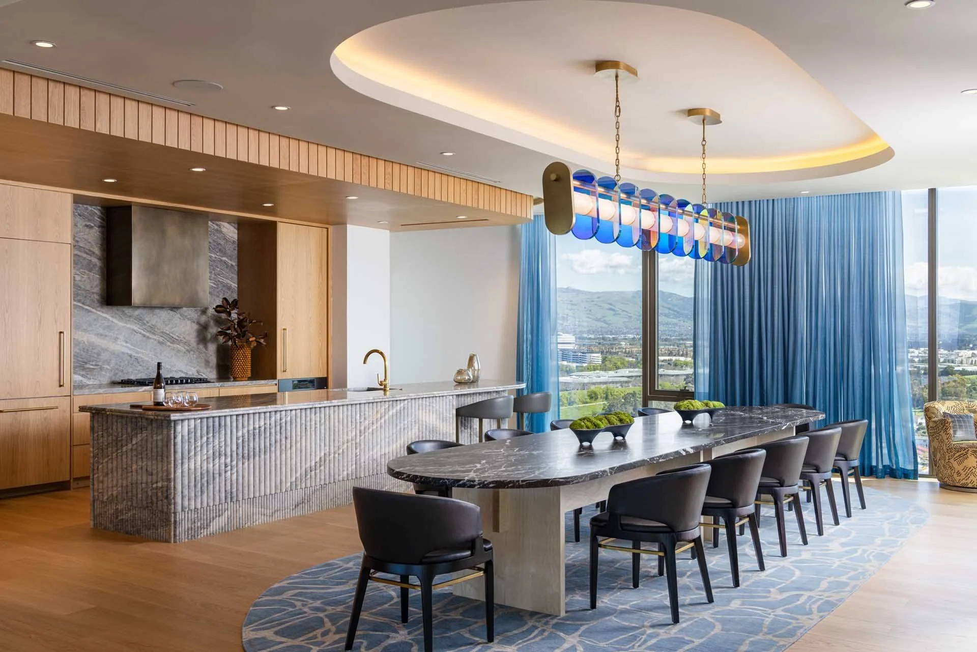 Private dining room with a stone island kitchen, long table and blue drapes, The Clara, Santa Clara