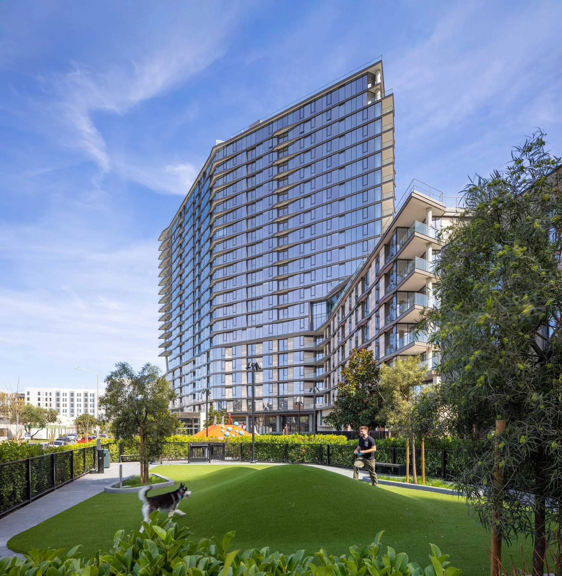 The Clara residential tower above a landscaped lawn and trees, Clara District, Santa Clara