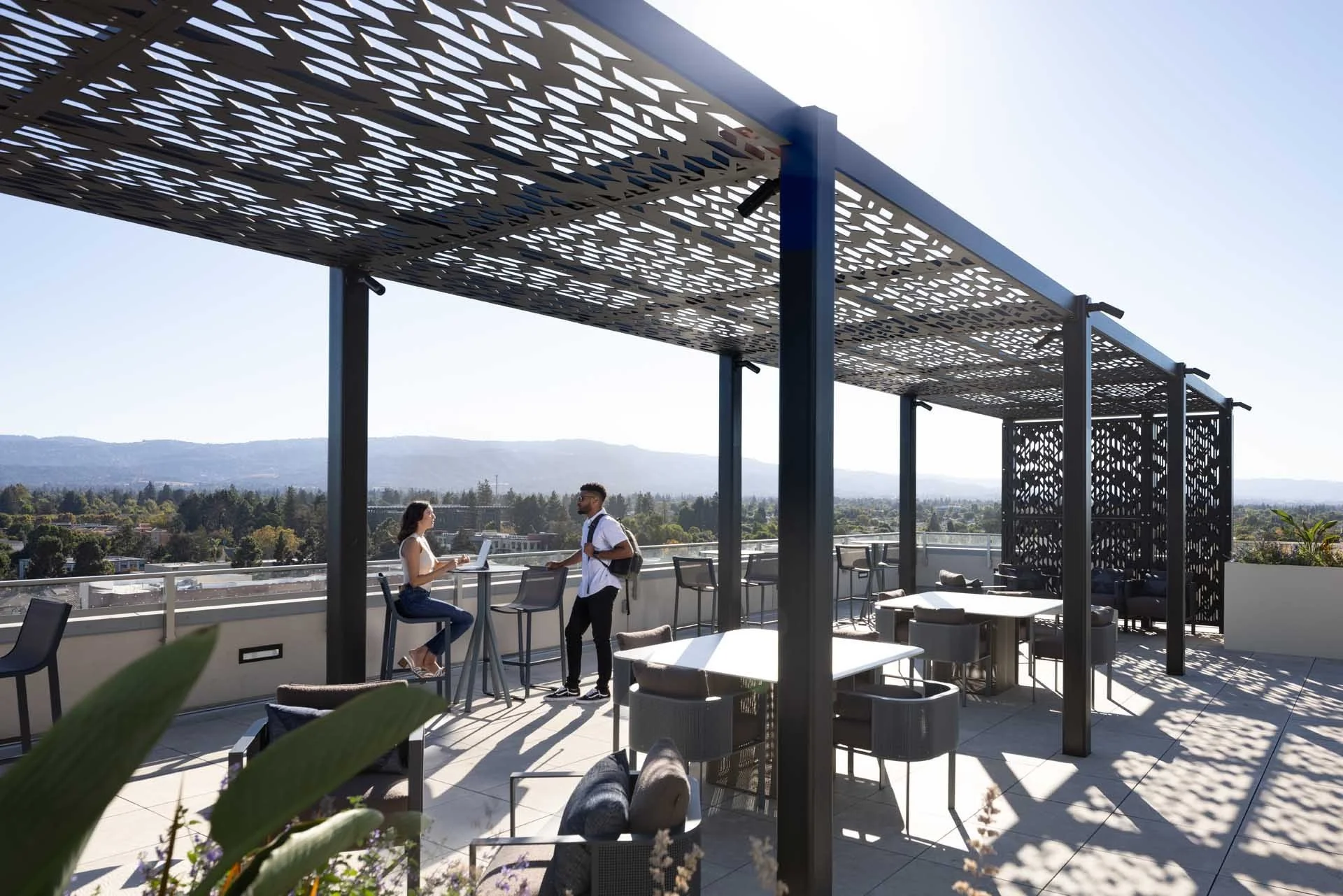 Roof terrace under a perforated metal pergola with dining tables and South Bay views, The Martin, Sunnyvale