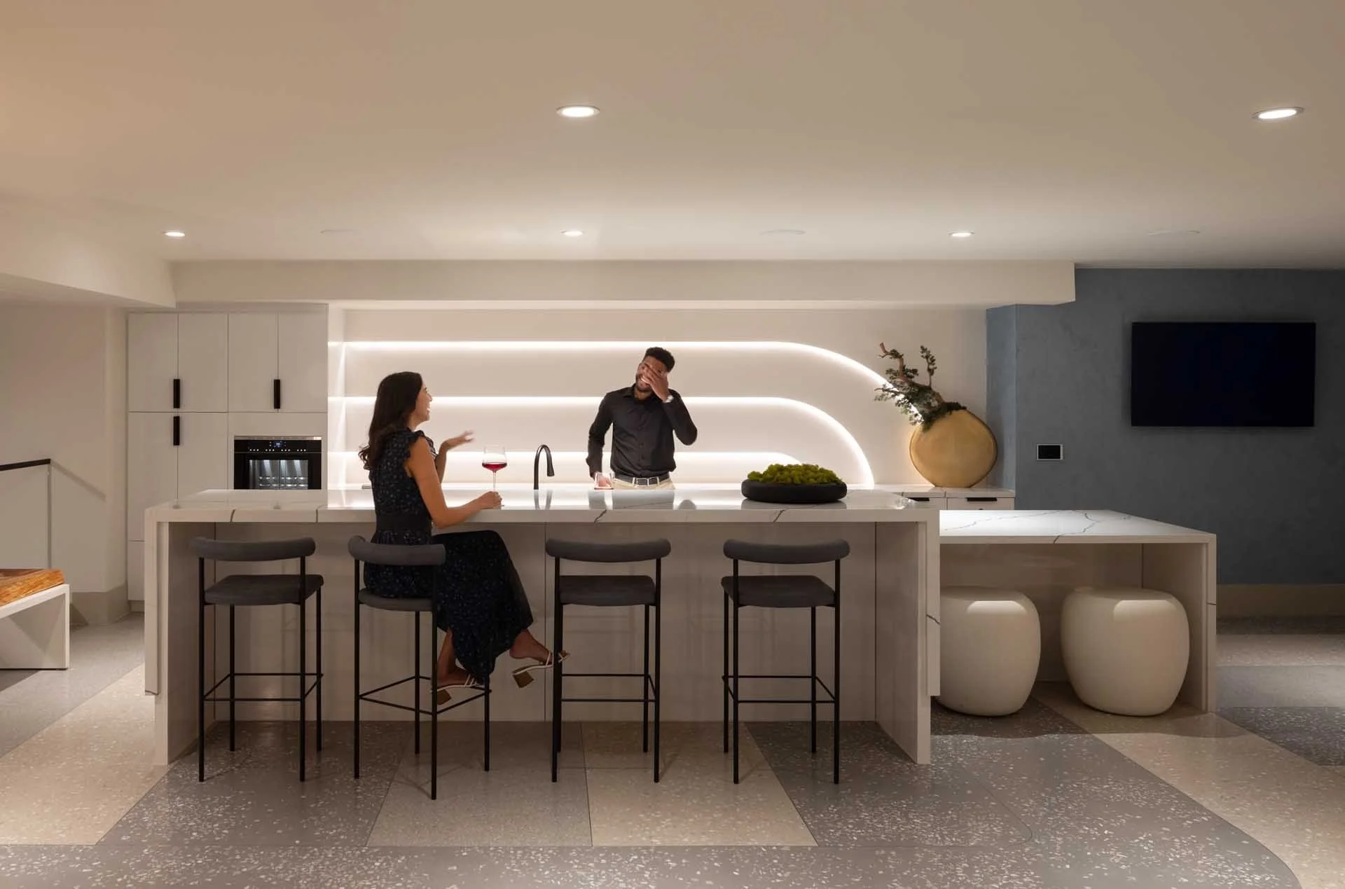 Resident demonstration kitchen with a curved white island and bar stools, The Martin at CityLine, Sunnyvale