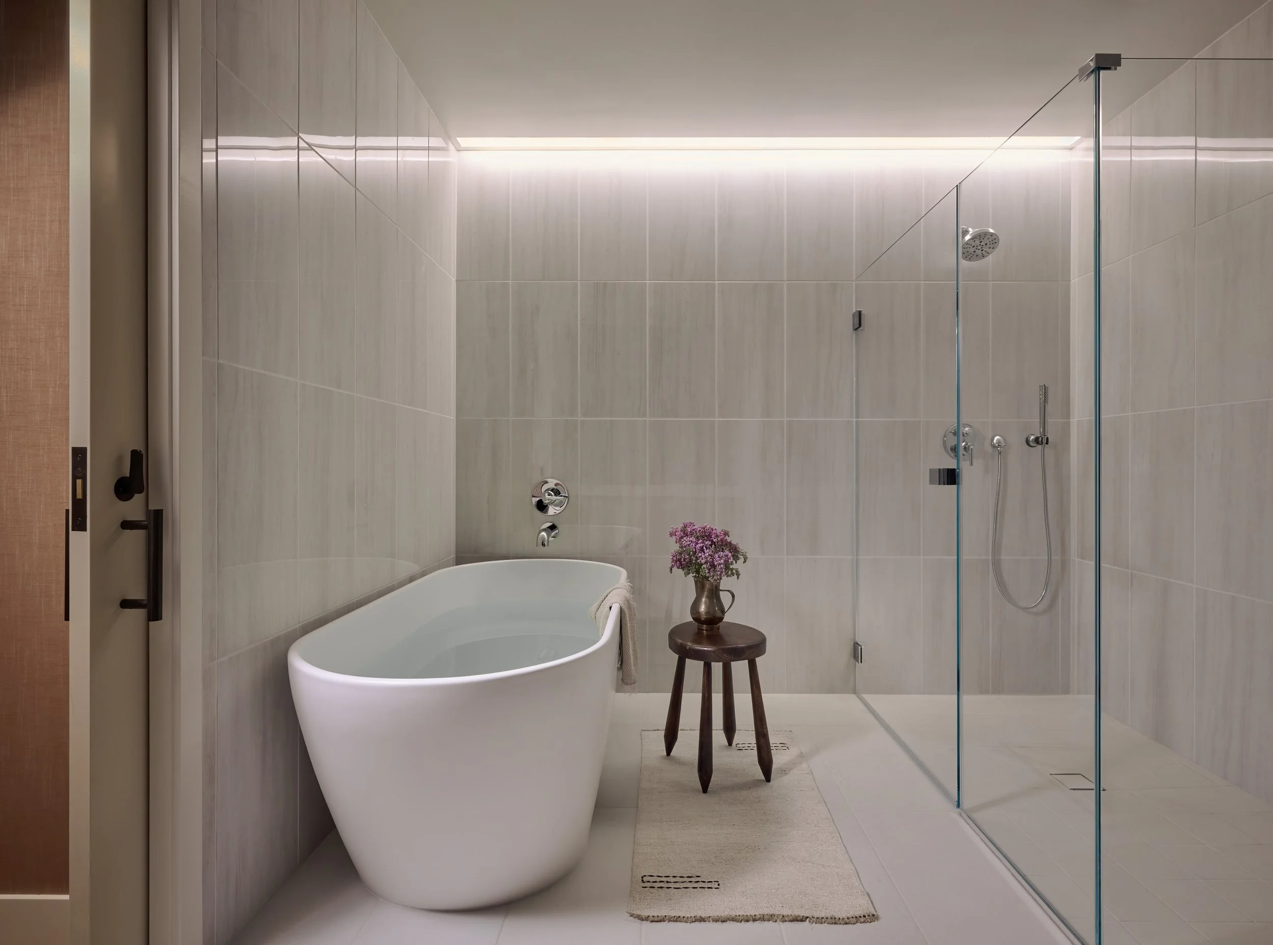 Primary bath with a freestanding tub and frameless glass shower in pale stone, 490 Avenue of the Palms, Treasure Island