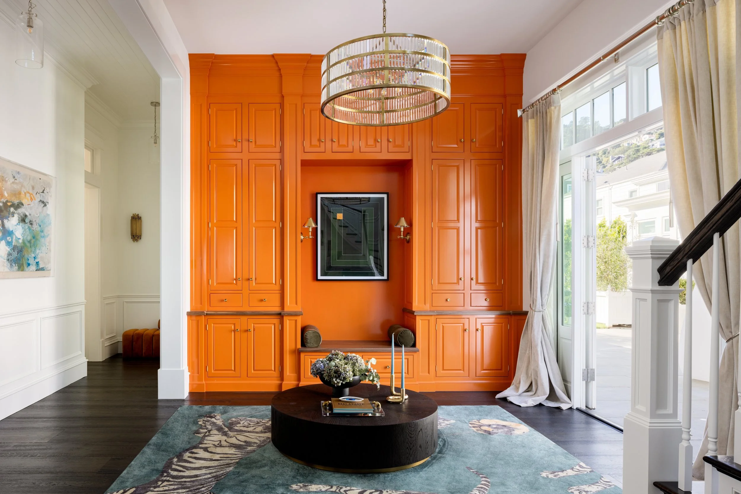Library with lacquered orange built-ins, a round brass chandelier and a teal rug, Valhalla, Sausalito