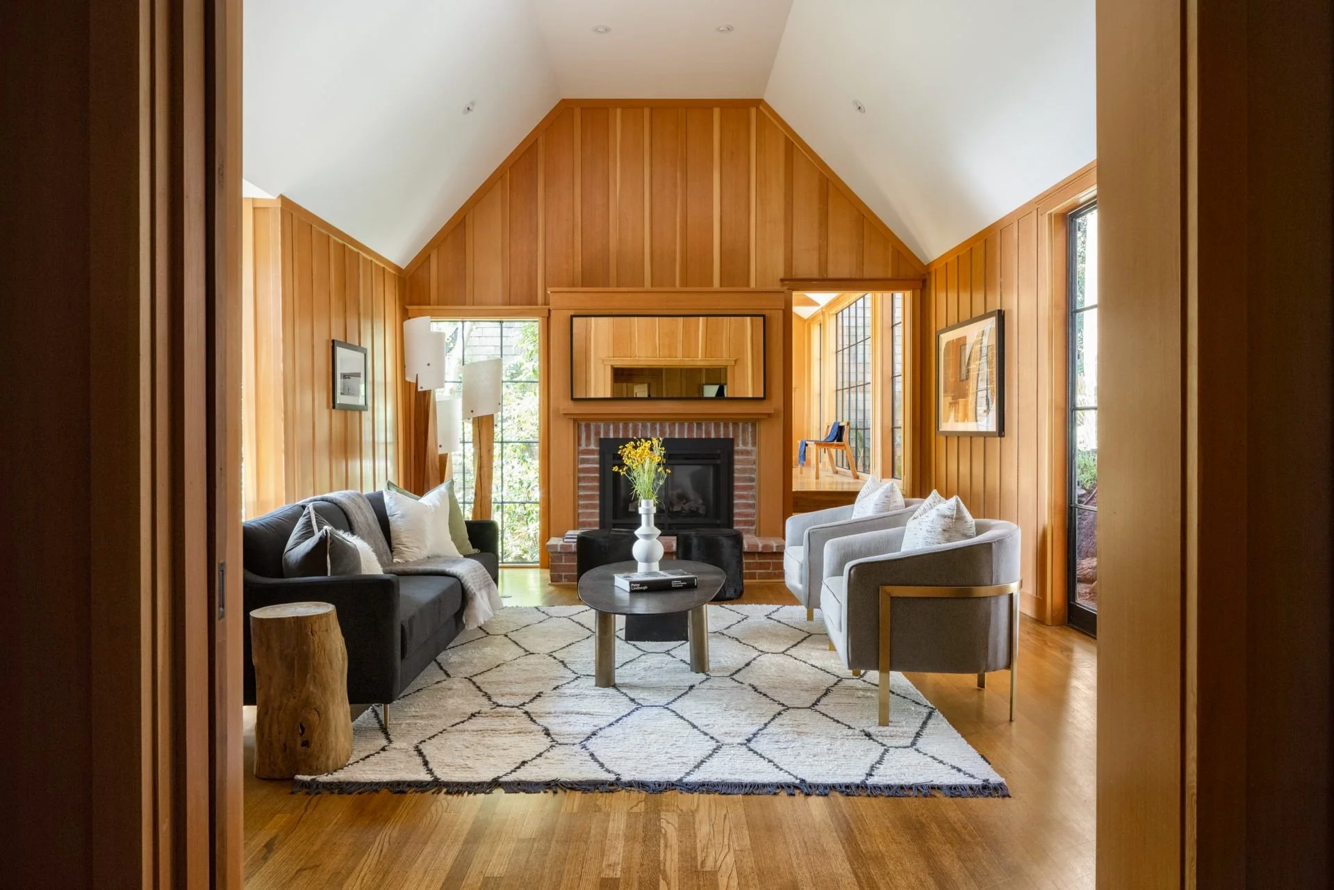Vaulted vertical-grain wood living room with a fireplace and woven rug, staged by Studio D Home, 16 Woodside, Mill Valley