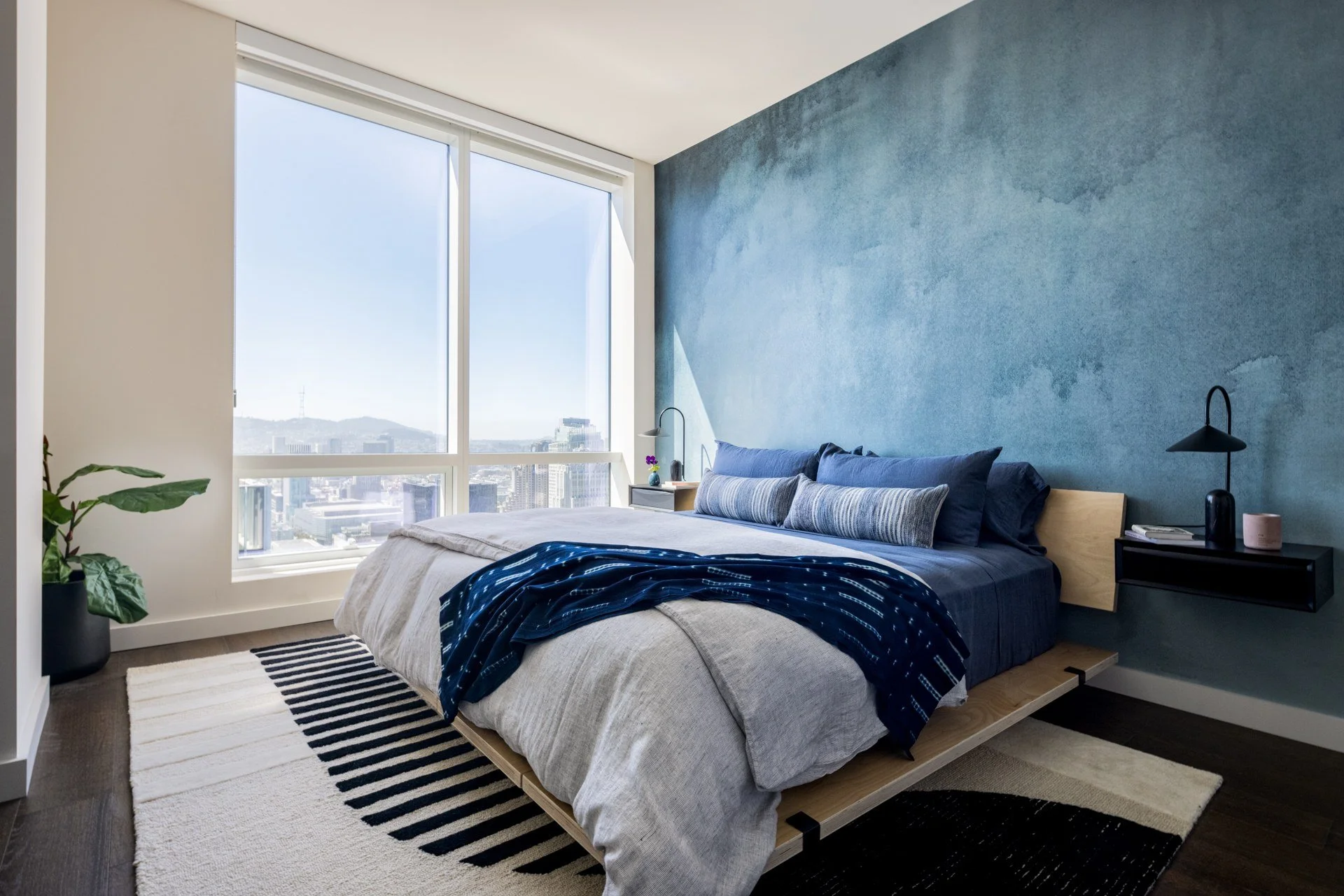 Bedroom with blue plaster wall and skyline views, The Avery, San Francisco