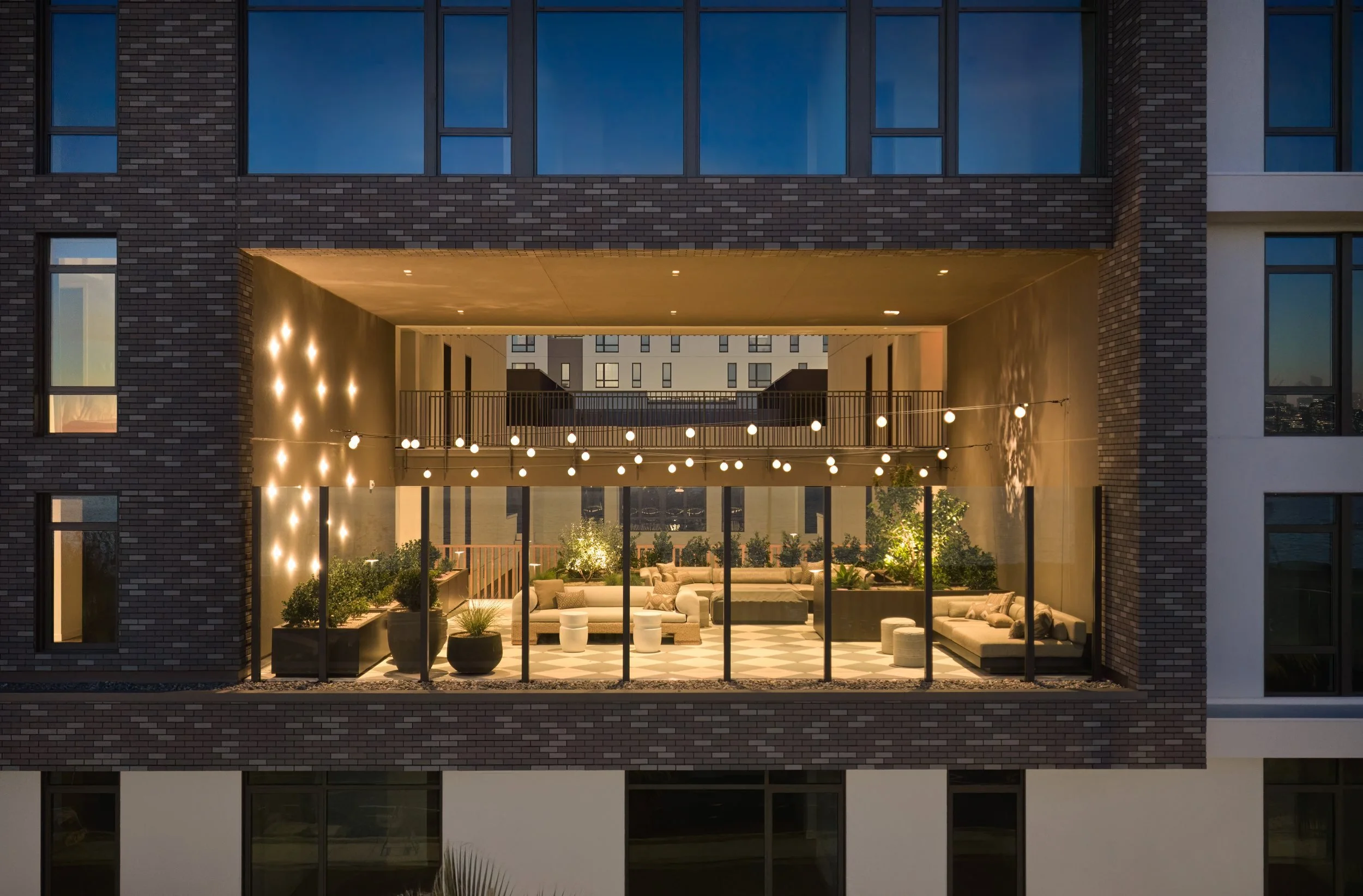 Glowing lobby portal cut through the brick facade at dusk, 490 Avenue of the Palms, Treasure Island