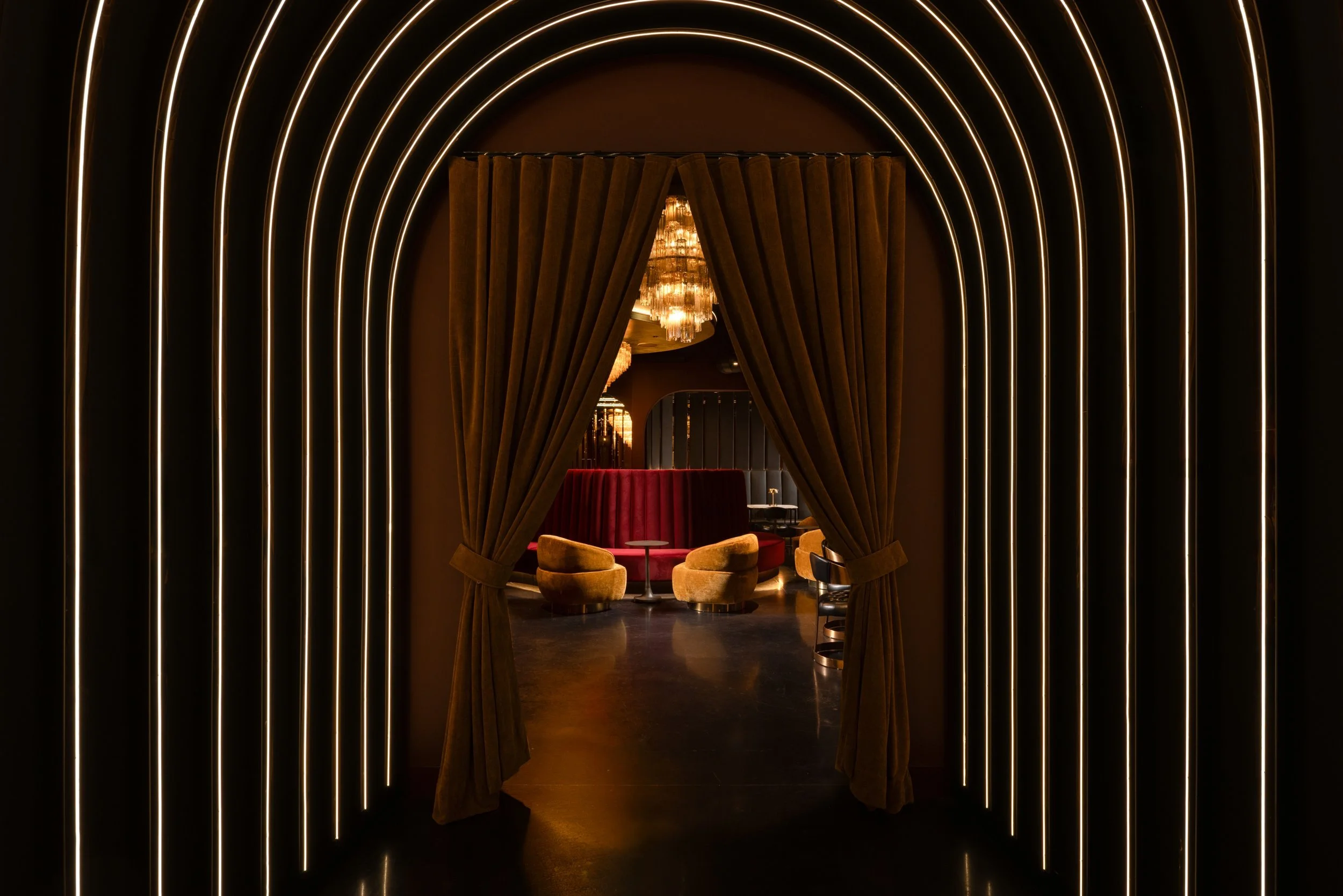 Arched entry of illuminated gold rings opening through velvet curtains into the bar, Matrix Bar, Napa