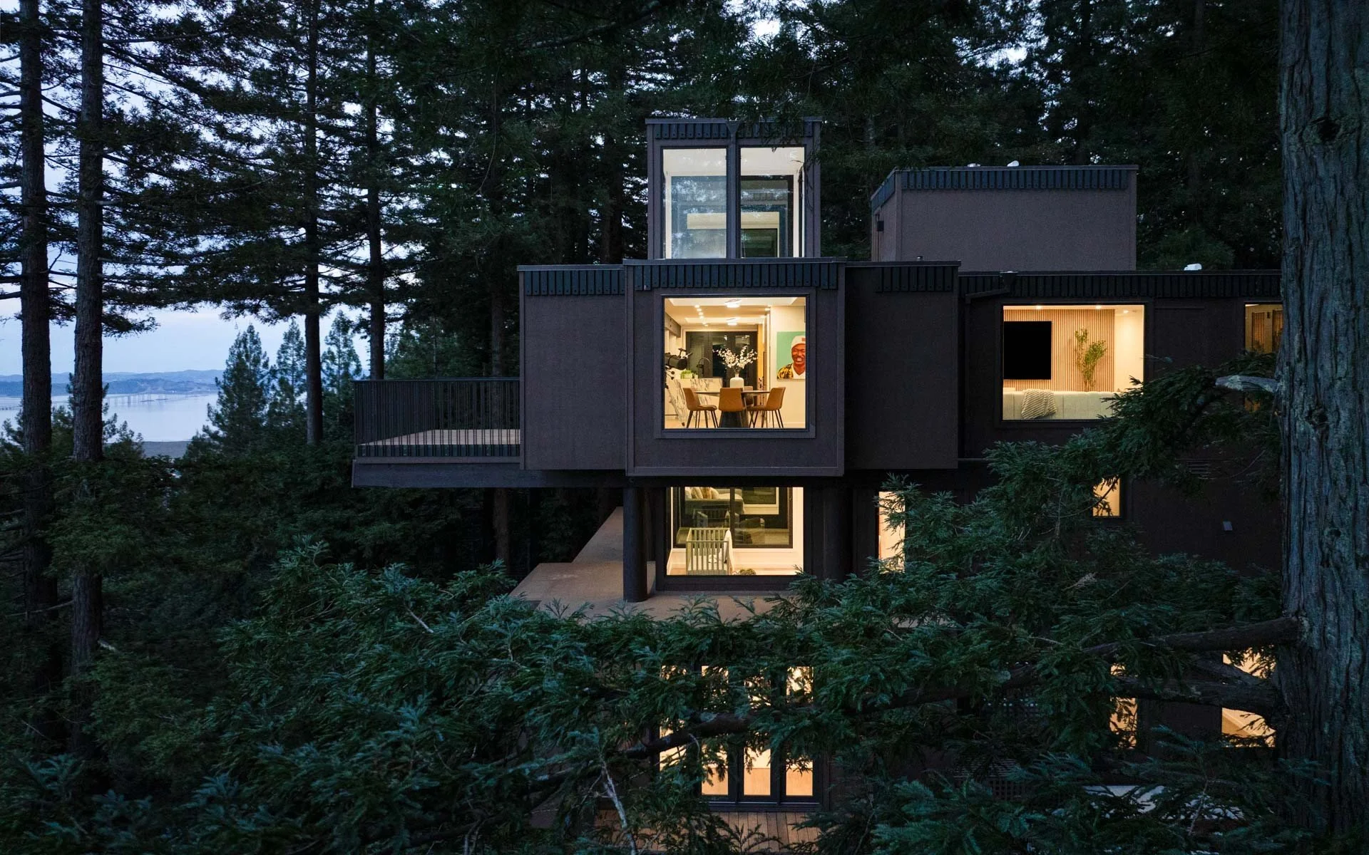 Aerial dusk view of the lit timber house rising through the redwood canopy, 238 Summit Drive, Corte Madera