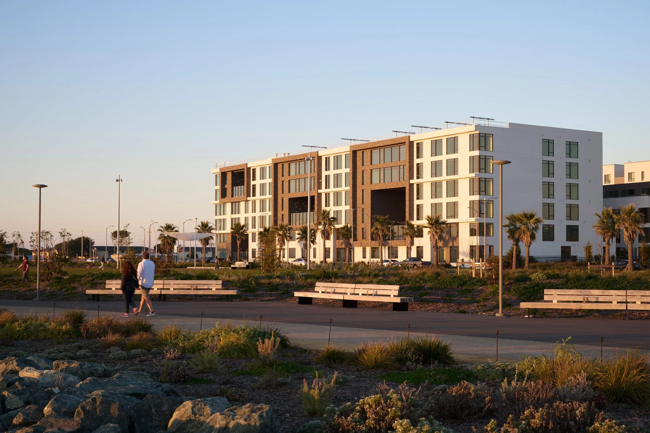 Six-story residential building at golden hour seen across Cityside Park, 490 Avenue of the Palms, Treasure Island