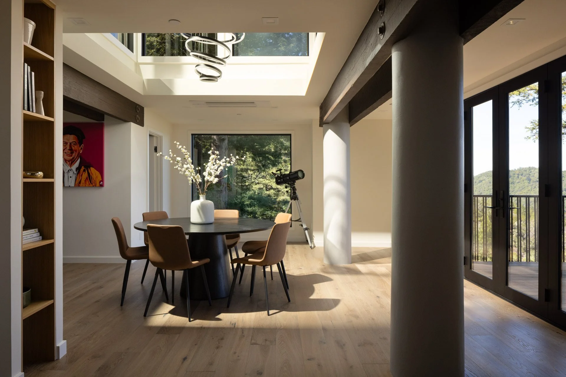 Dining area under a skylight with a ring chandelier and doors to a redwood-view deck, 238 Summit Drive, Corte Madera