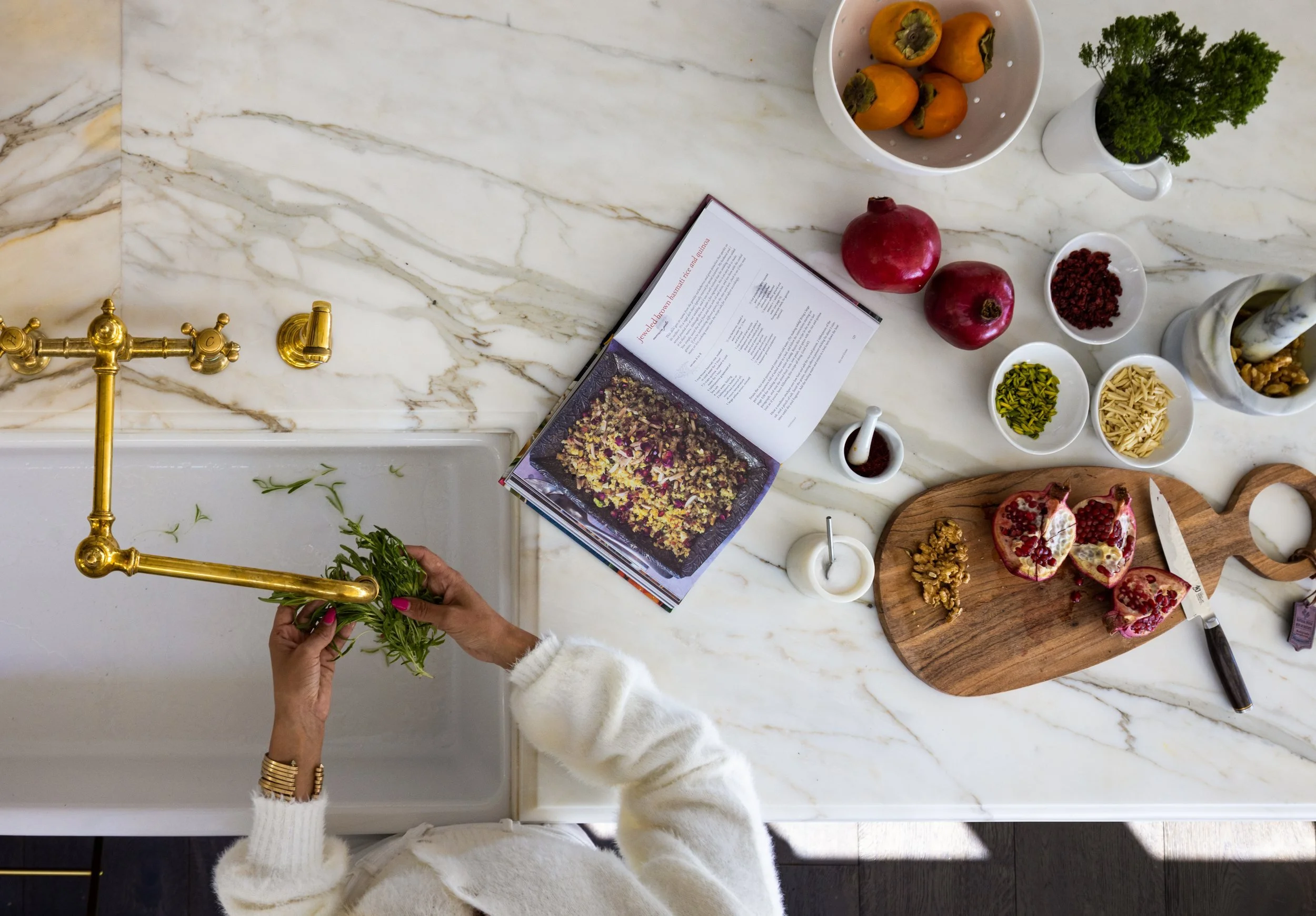 Overhead of a marble counter with a brass faucet, cookbook and a styled spread of fruit, Valhalla, Sausalito