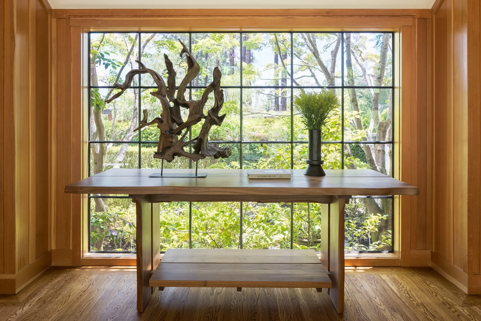 Console table with a driftwood sculpture before a steel-framed window onto the forest, 16 Woodside, Mill Valley