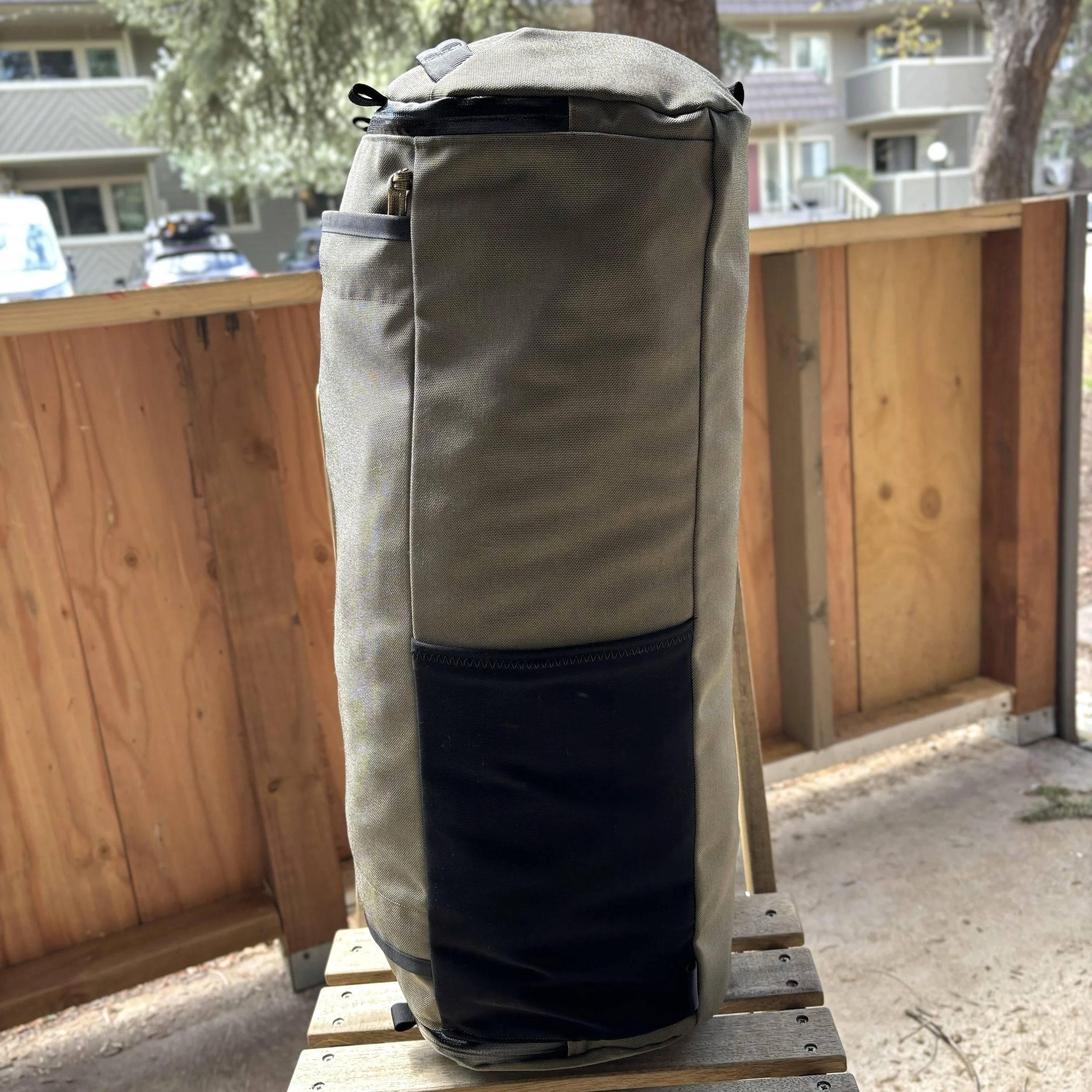 Gray and black backpack sitting on a wooden bench outdoors