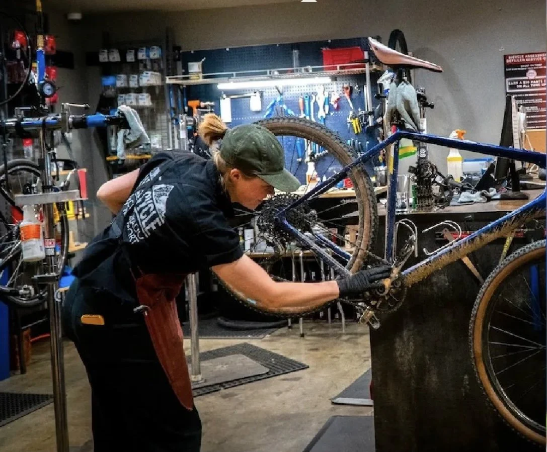 Bicycle mechanic servicing a muddy mountain bike in a professional repair shop