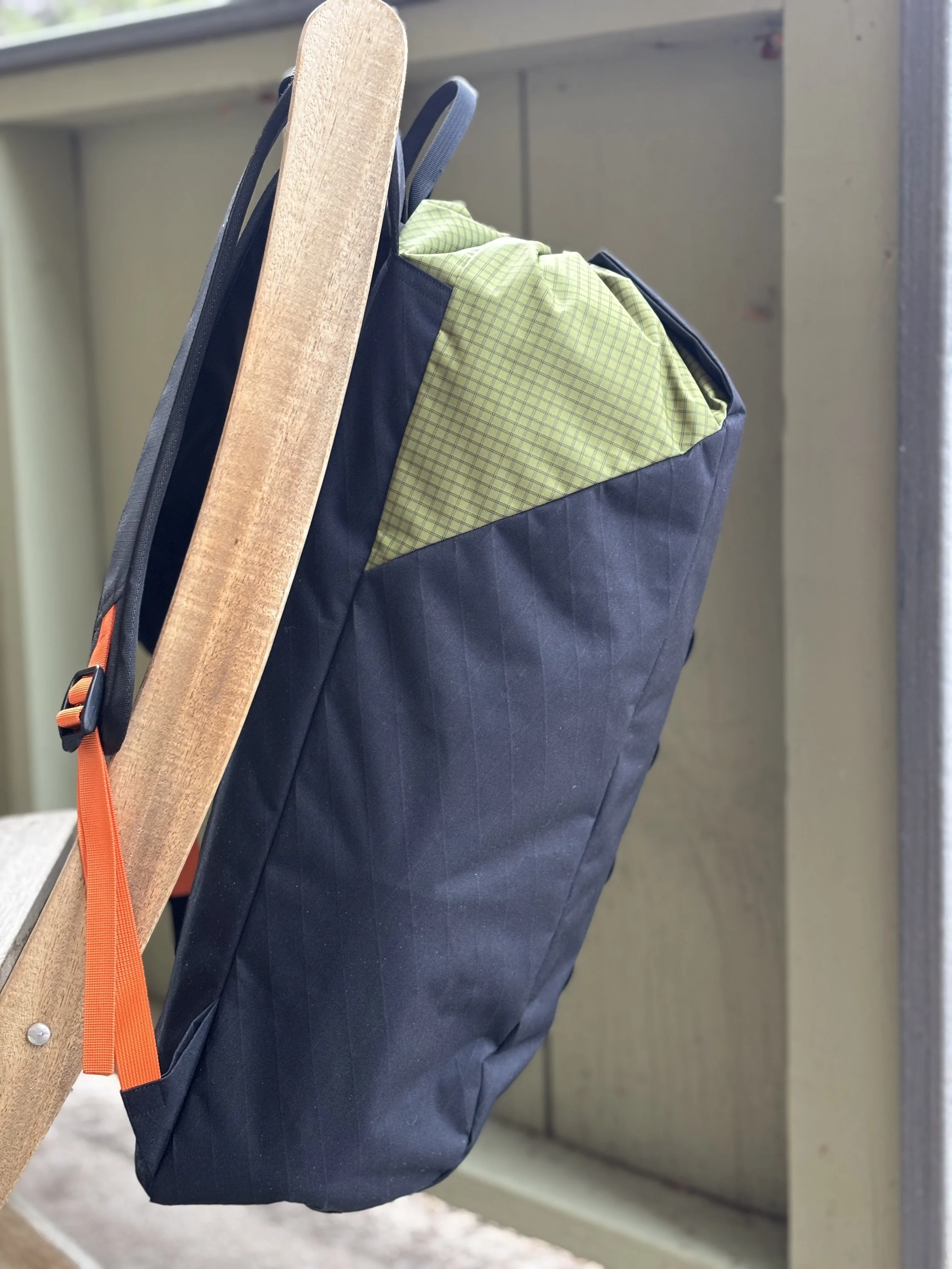 Navy gear bag with green plaid lining strapped to a wooden board using orange straps