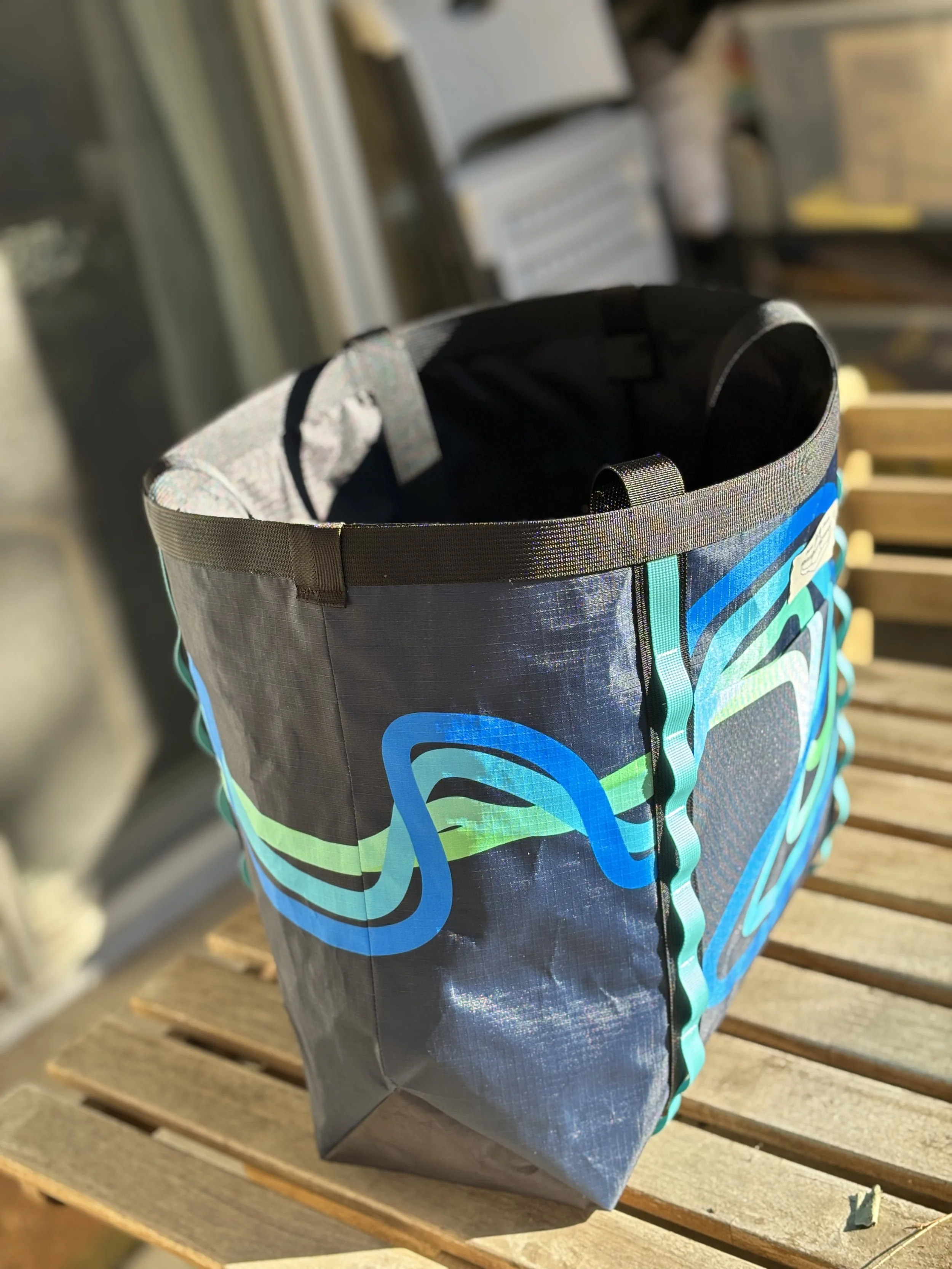 Open black and blue patterned backpack resting on a wooden bench, with clothing visible inside.