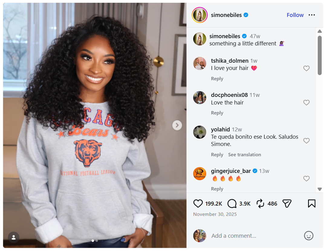 Simone Biles smiling and wearing a gray Chicago Bears sweatshirt with voluminous curly hair in an Instagram post