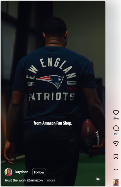 Person wearing a New England Patriots T-shirt and holding a football, in a dim hallway.